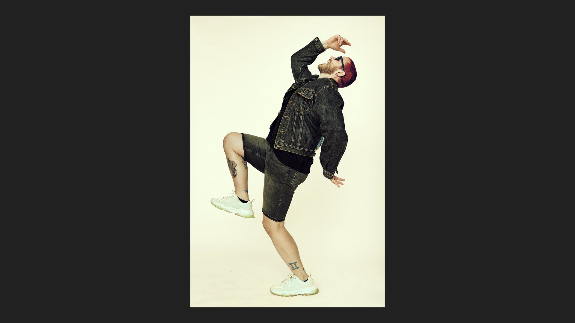 Man screaming and jumping wearing jean shorts and jacket.