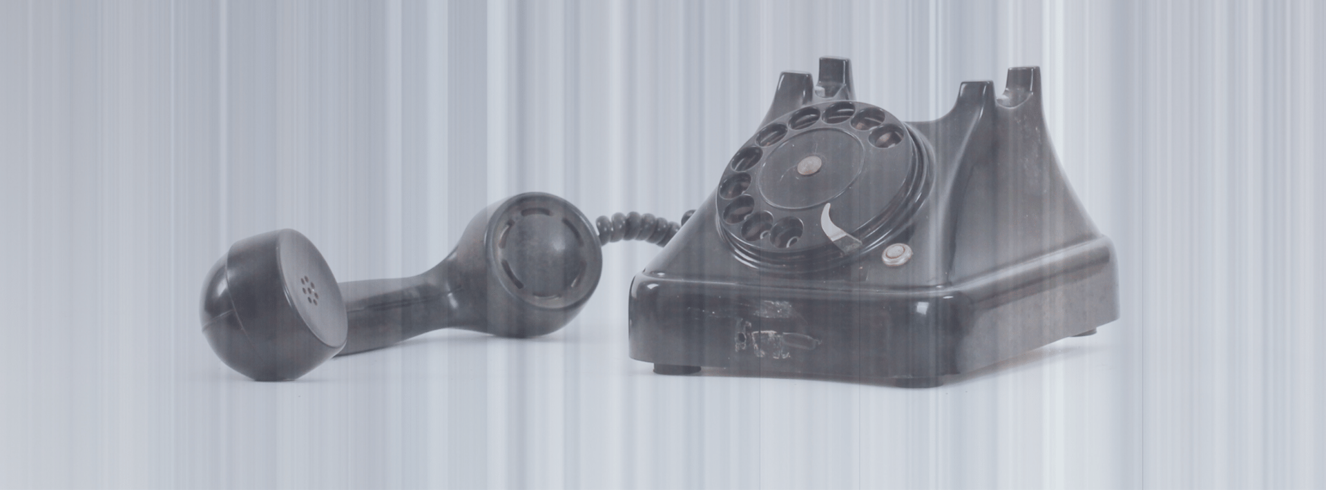 photo of black rotary phone against white background