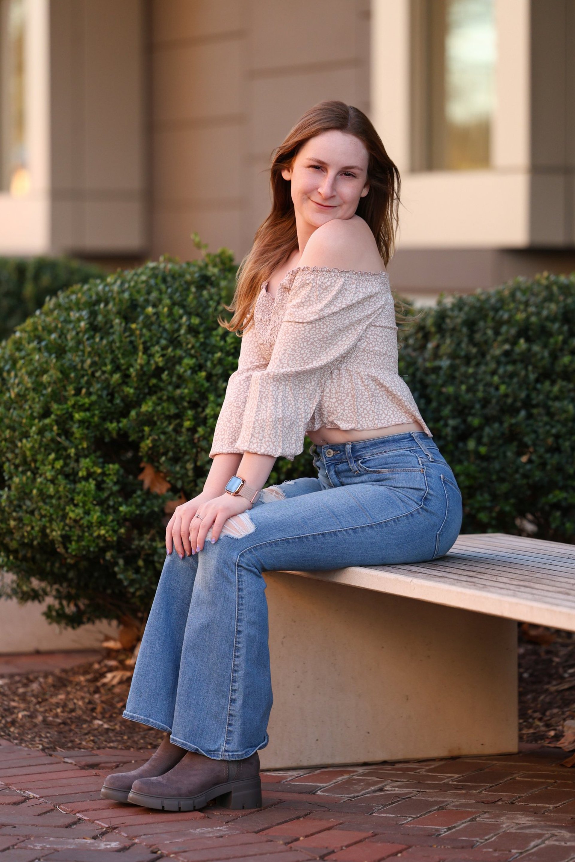 woman in black long sleeve shirt and blue denim jeans sitting on white concrete wall