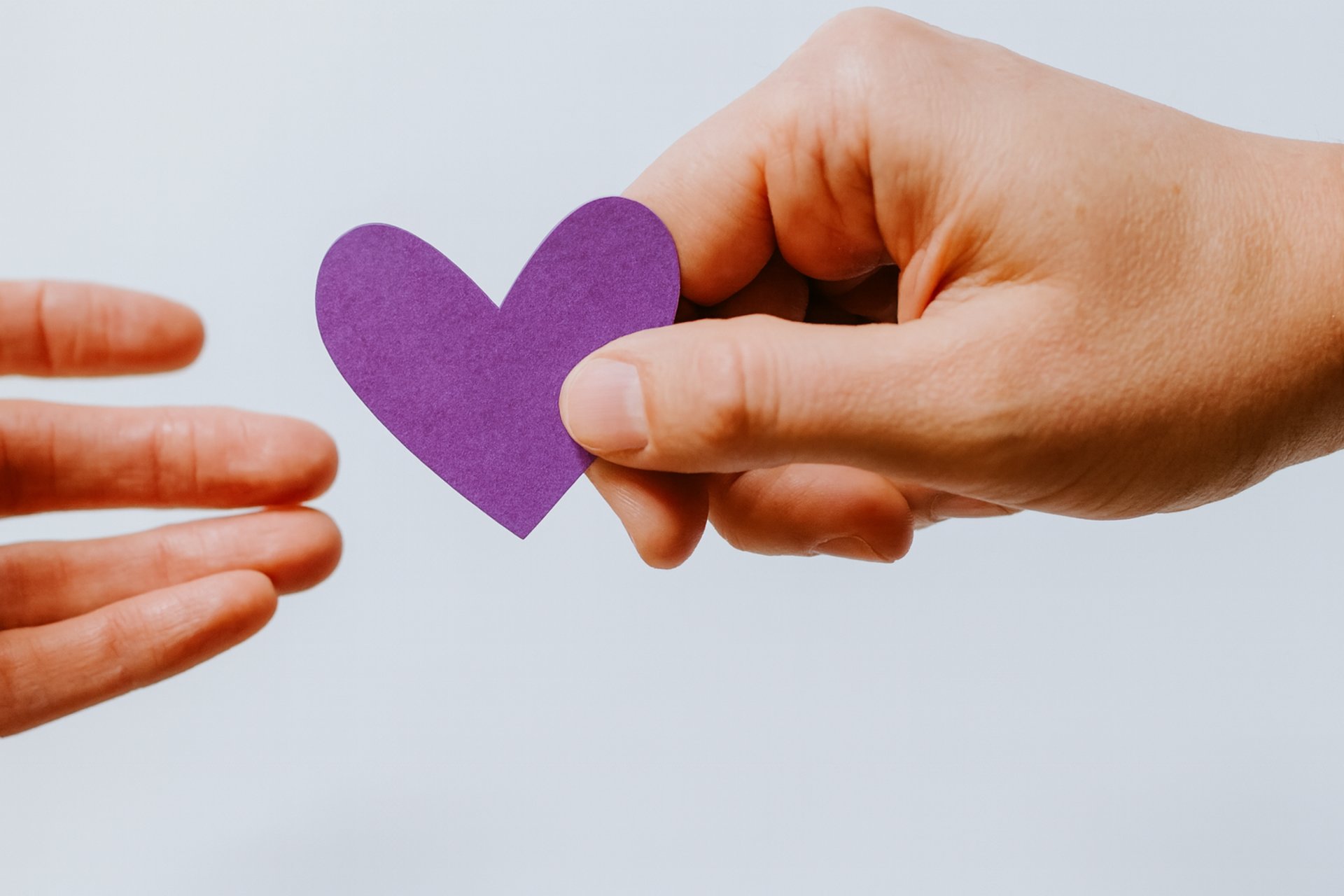 person reaching black heart cutout paper