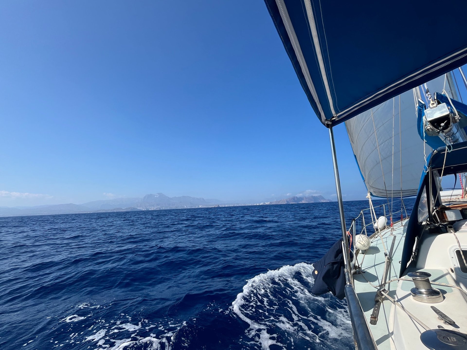 white boat on sea under blue sky and white clouds during daytime