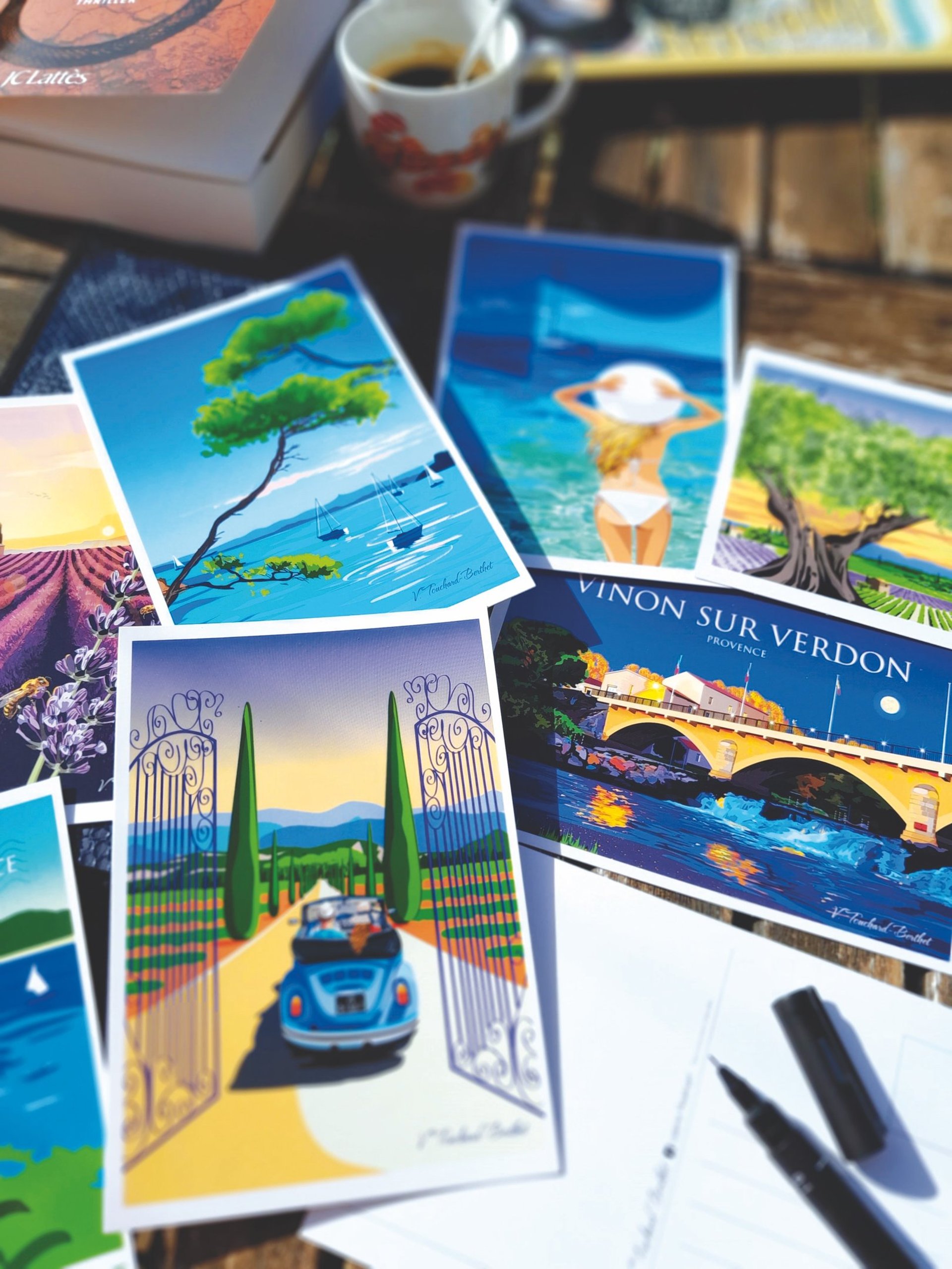 Cartes postales de paysages de Provence posées sur une table en pèle-mêle.
