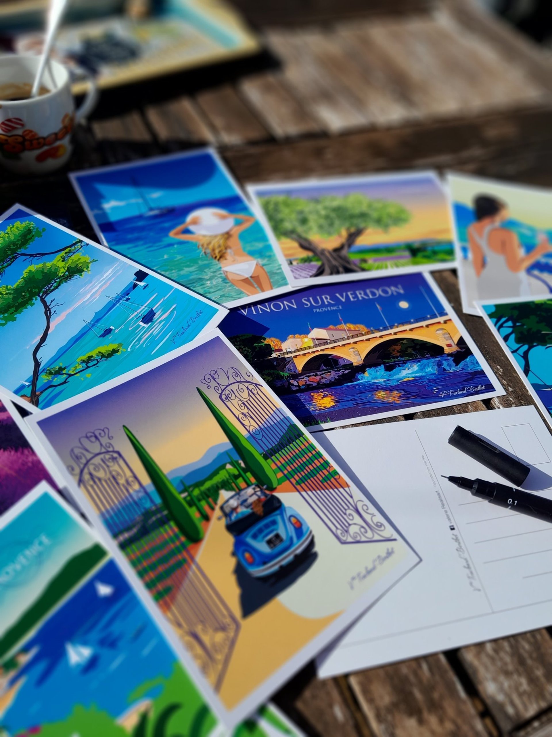 Cartes postales de paysages de Provence posées sur une table en pèle-mêle.