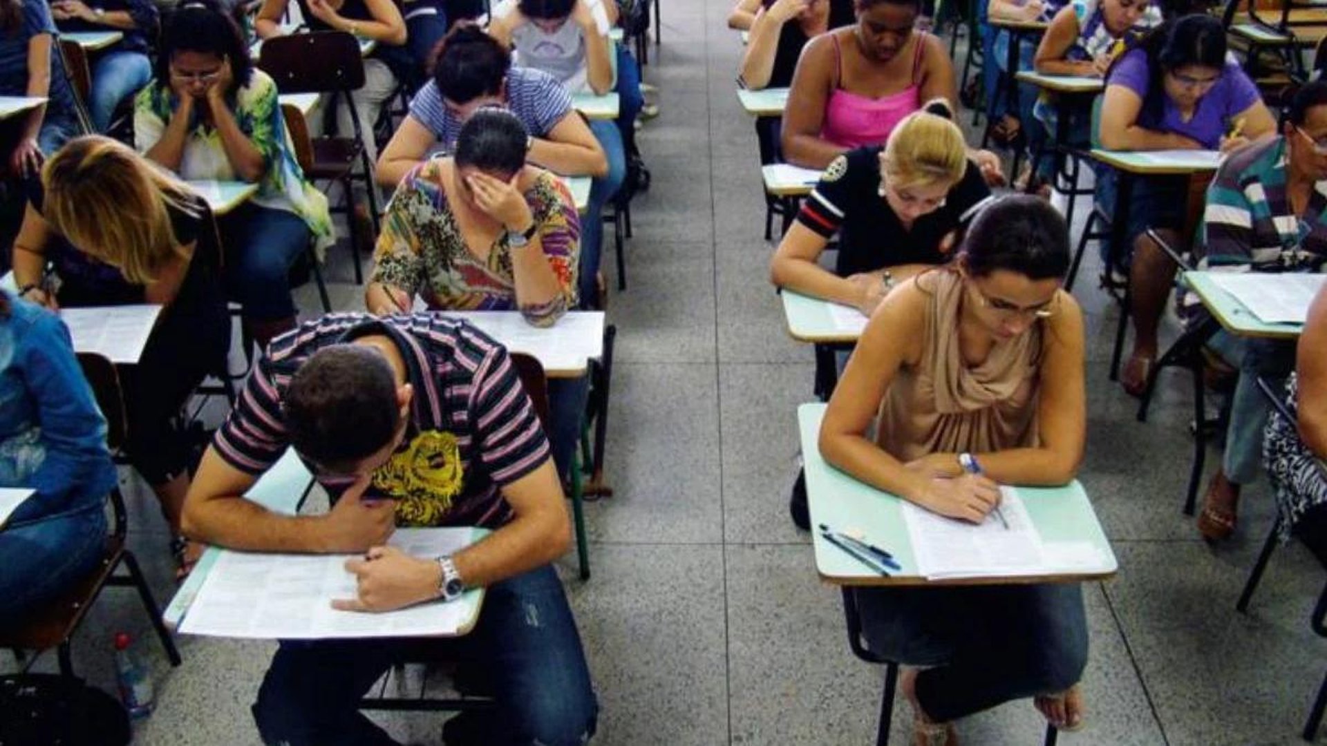 person writing on brown wooden table near white ceramic mug