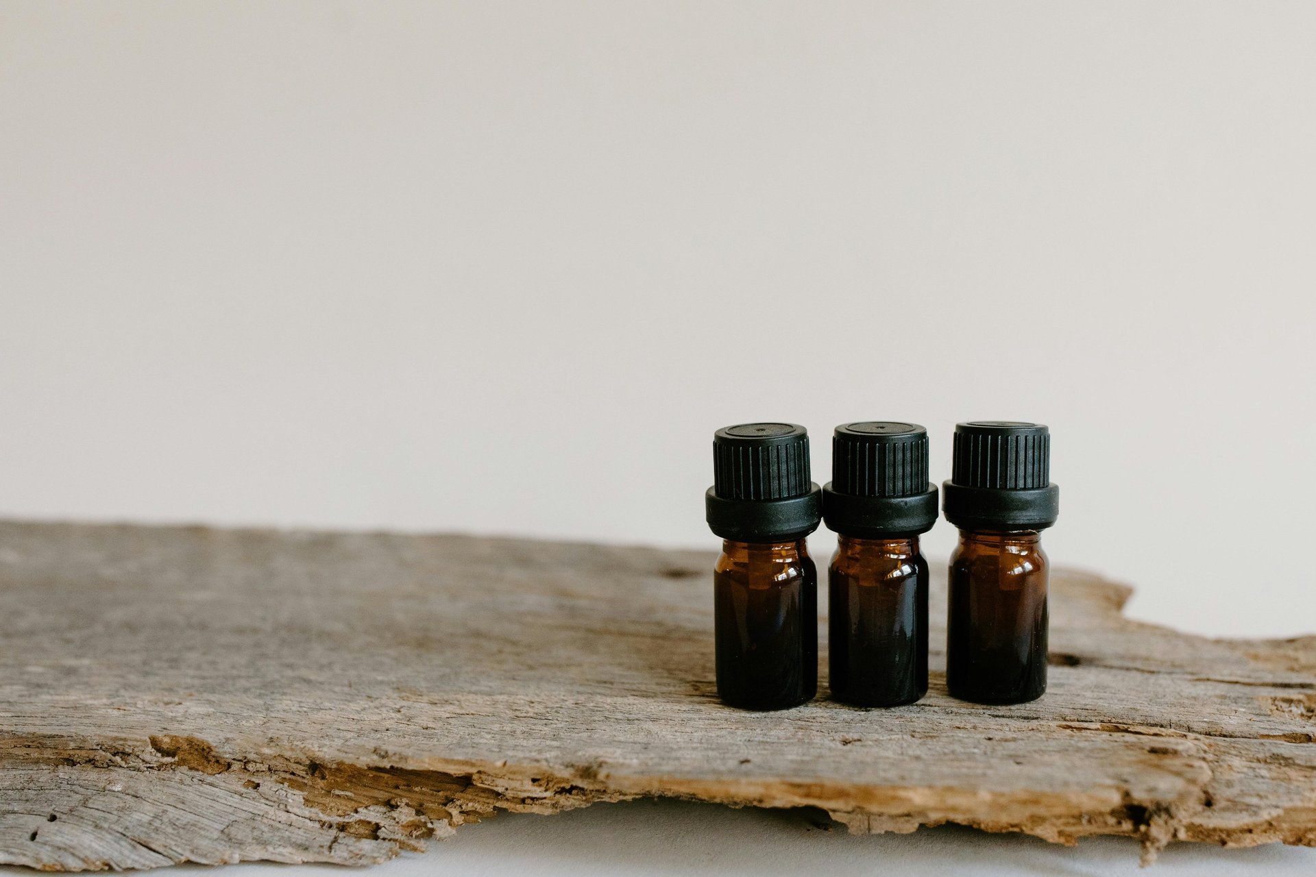 Three essential oil bottles on a natural piece of wood