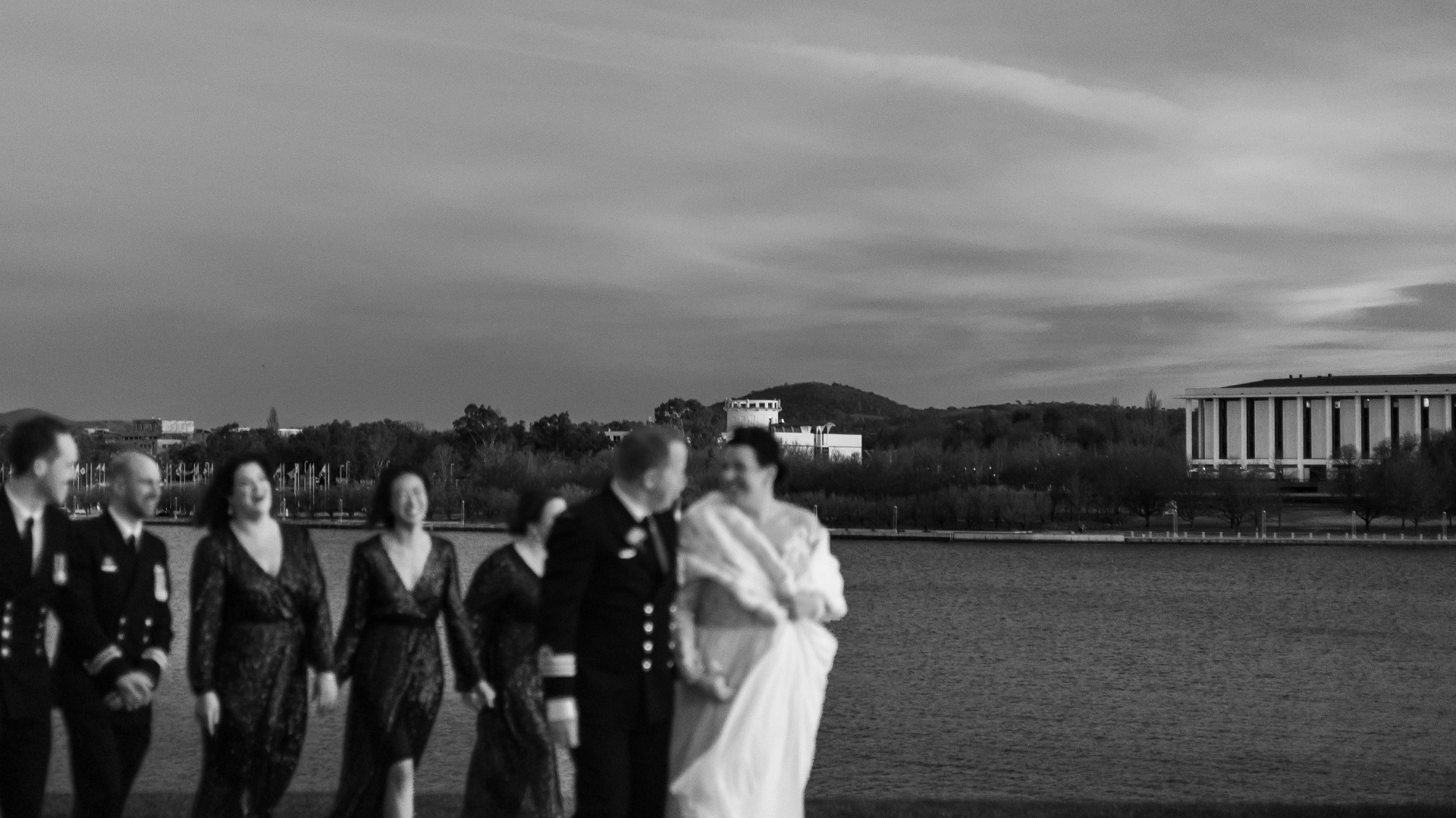 Bride and groom walking hand in hand through sparker exit, guests smiling, Canberra wedding photographer capturing moments