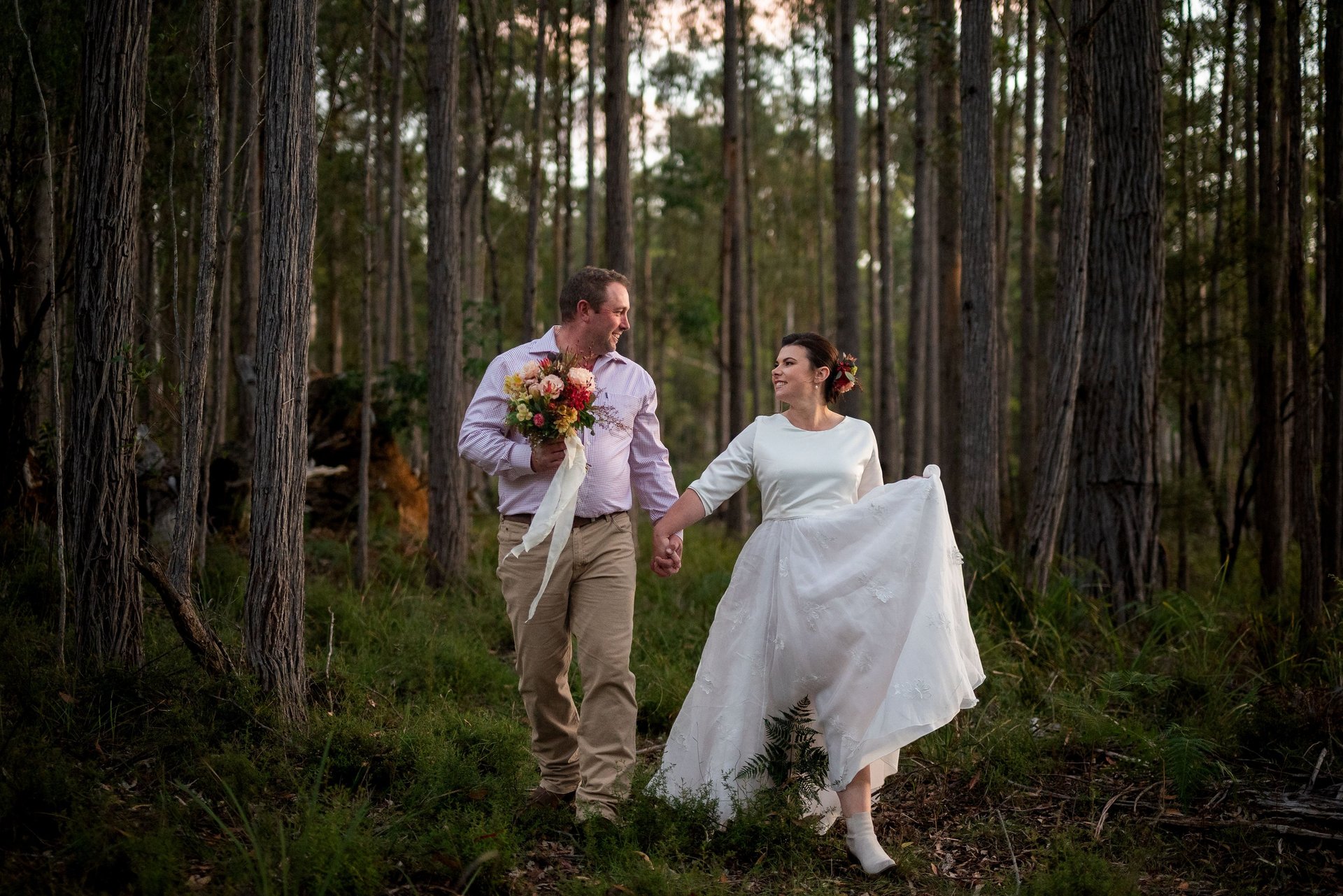 Bride and groom standing together smiling, black and white image with big tree in the background. Canberra wedding photograph