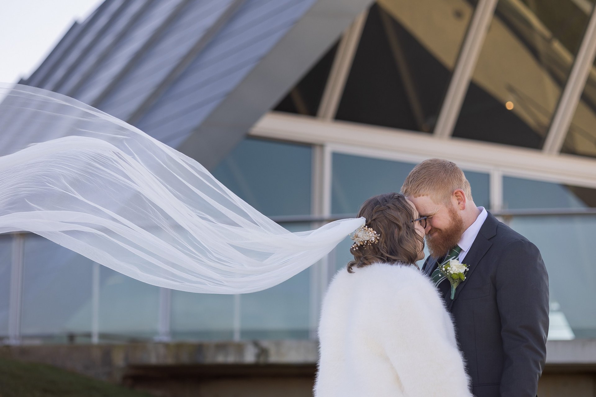 Bride and groom standing face to face, her veil flowing behind. Canberra wedding photographer.