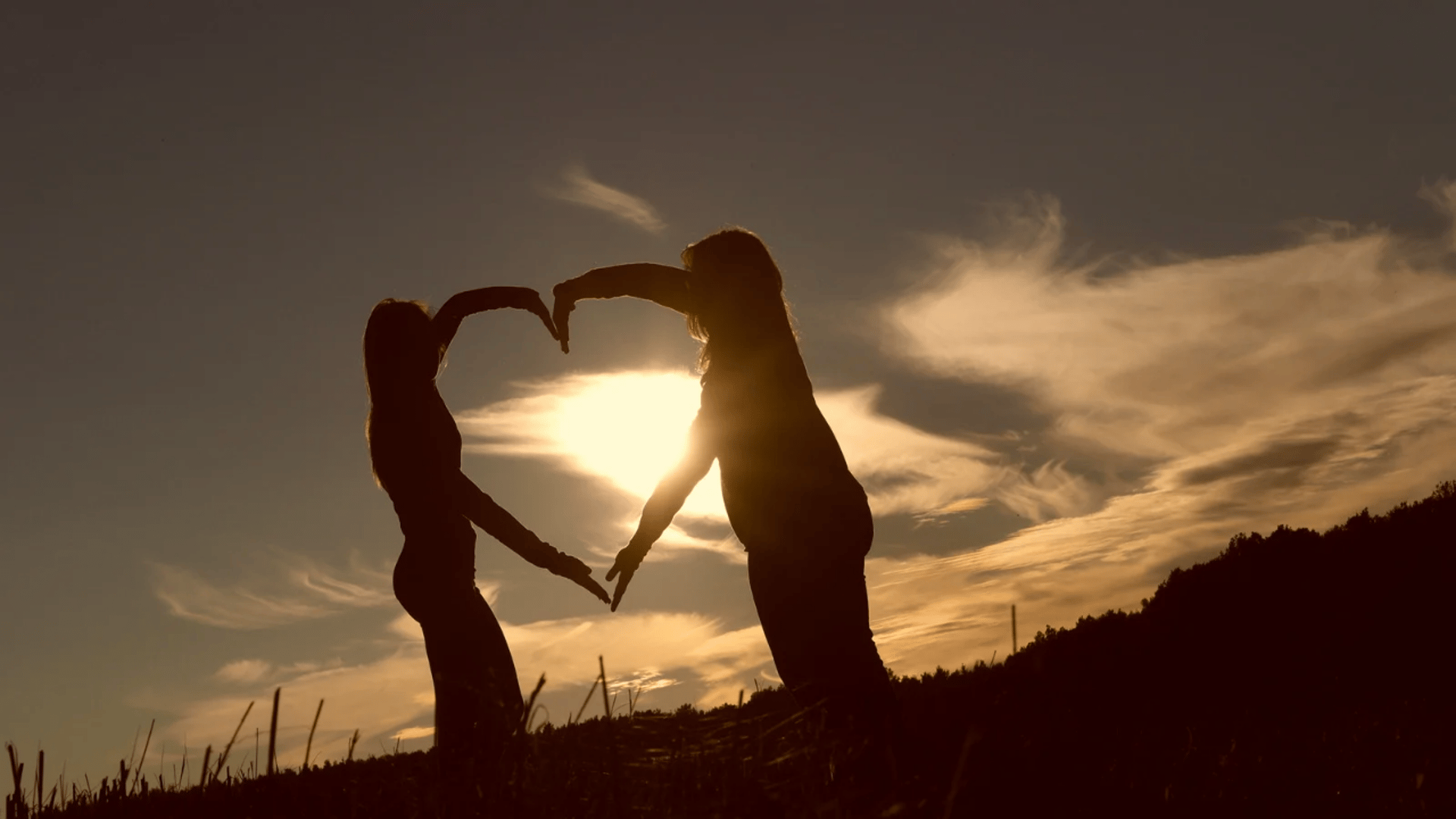 person doing heart shape hand with sun light passing thru