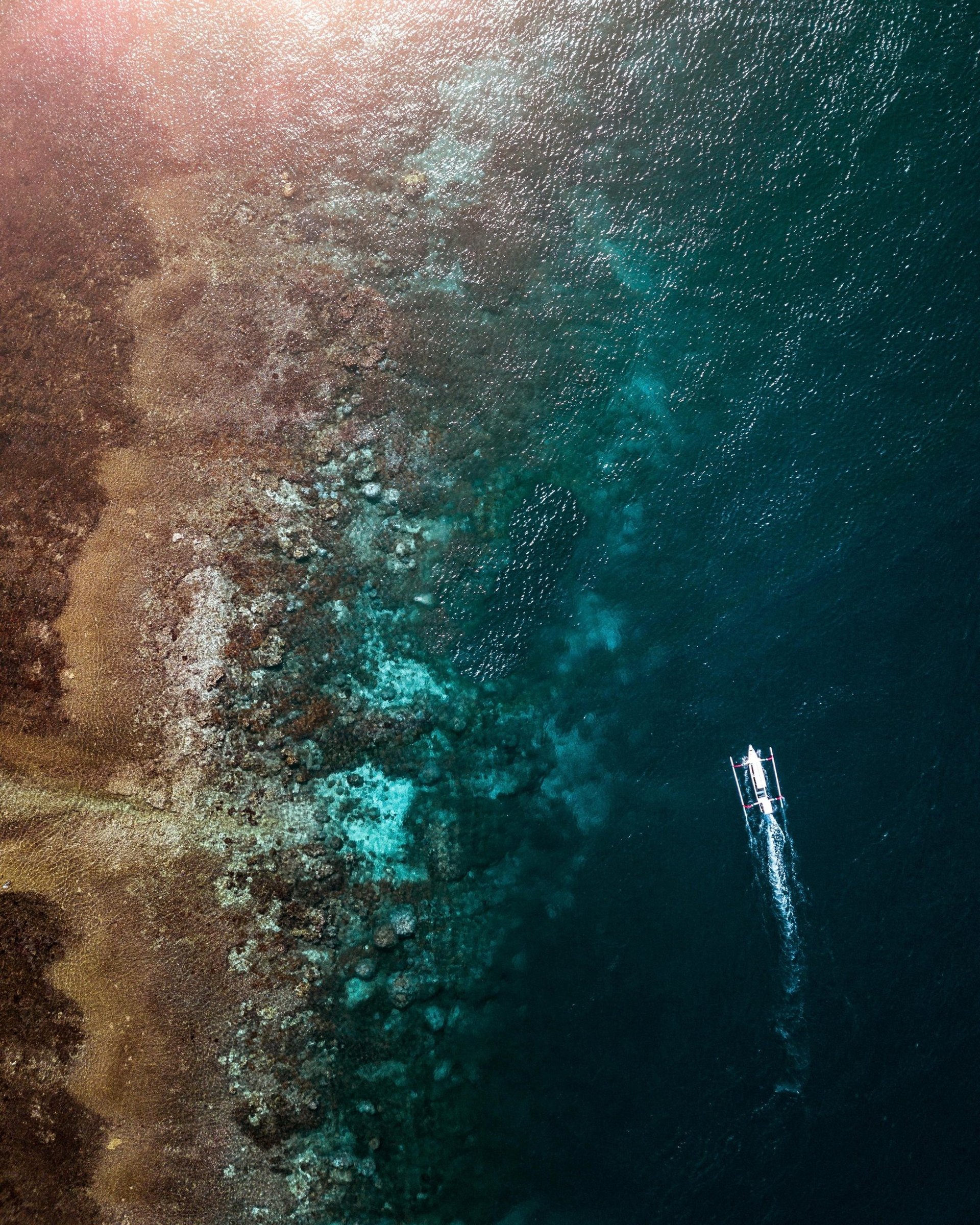 Encontro do mar azul, com parte de água translúcida onde se vê a junção entre as pedras e a água.