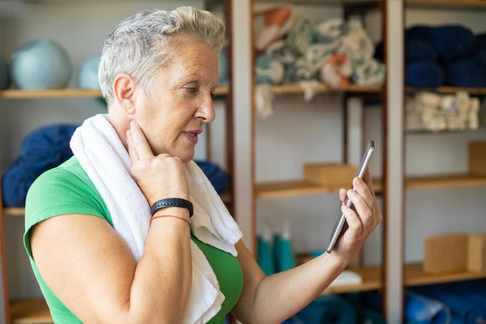 Elderly adult woman taking her pulse while looking at her phone