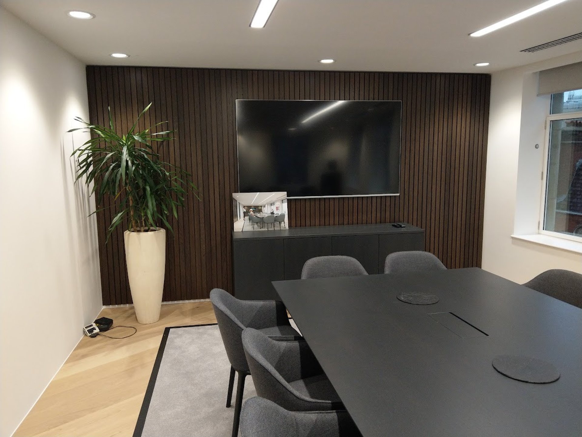 77" TV mounted on a wall in a boardroom