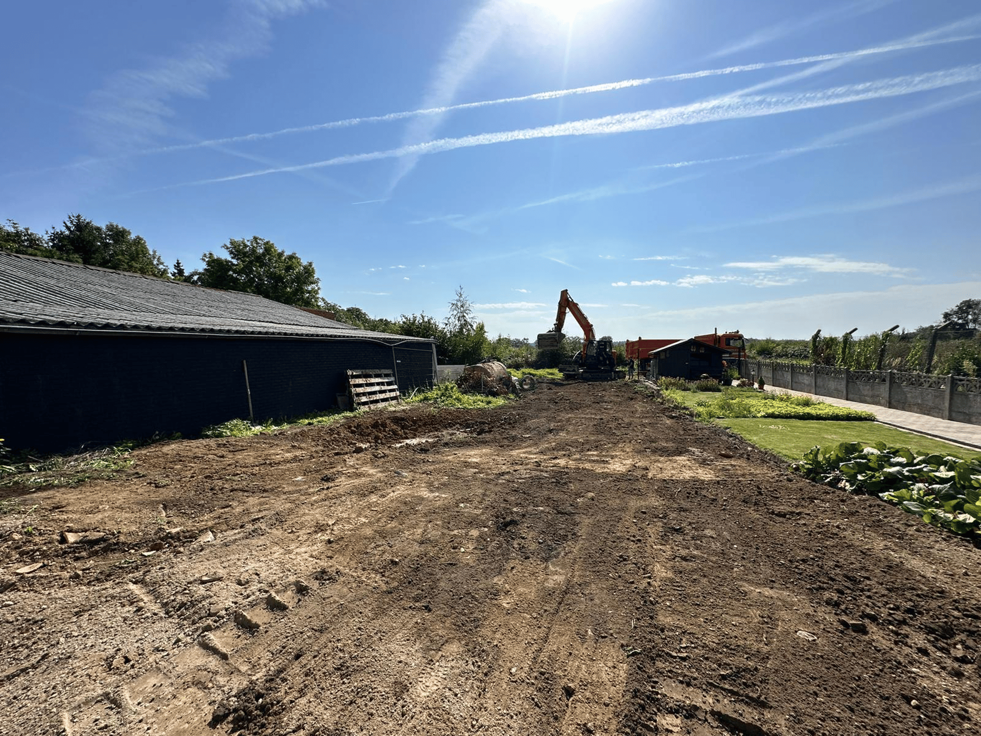 A green and orange truck parked next to a forest