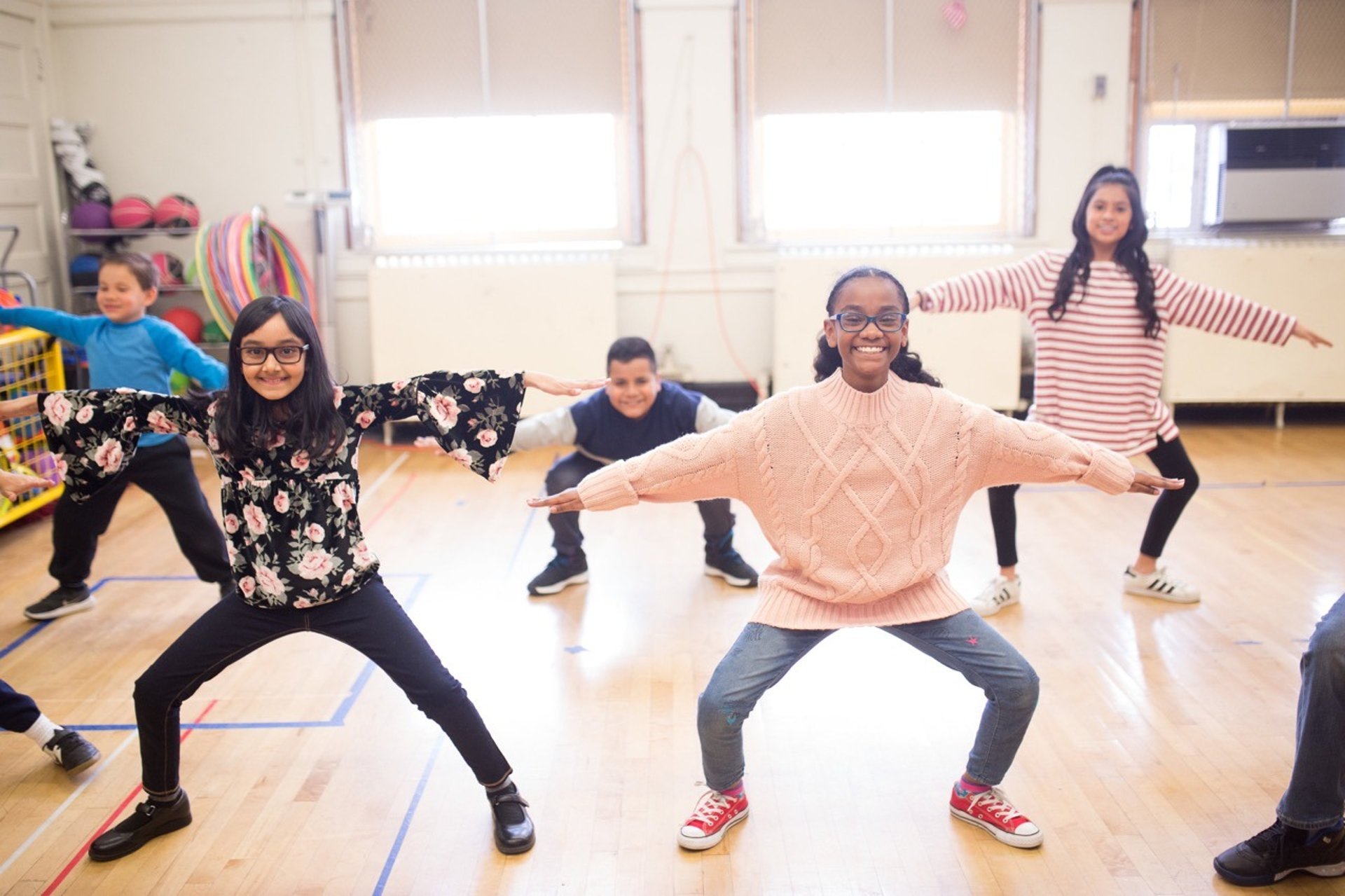 Elementary students to a squat exercise.