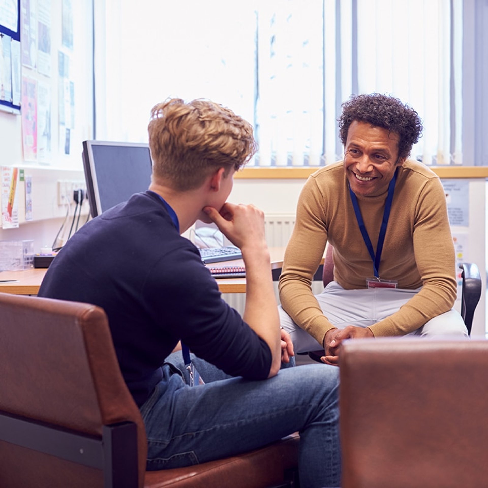 man wearing white and black plaid button-up sports shirt pointing the silver MacBook
