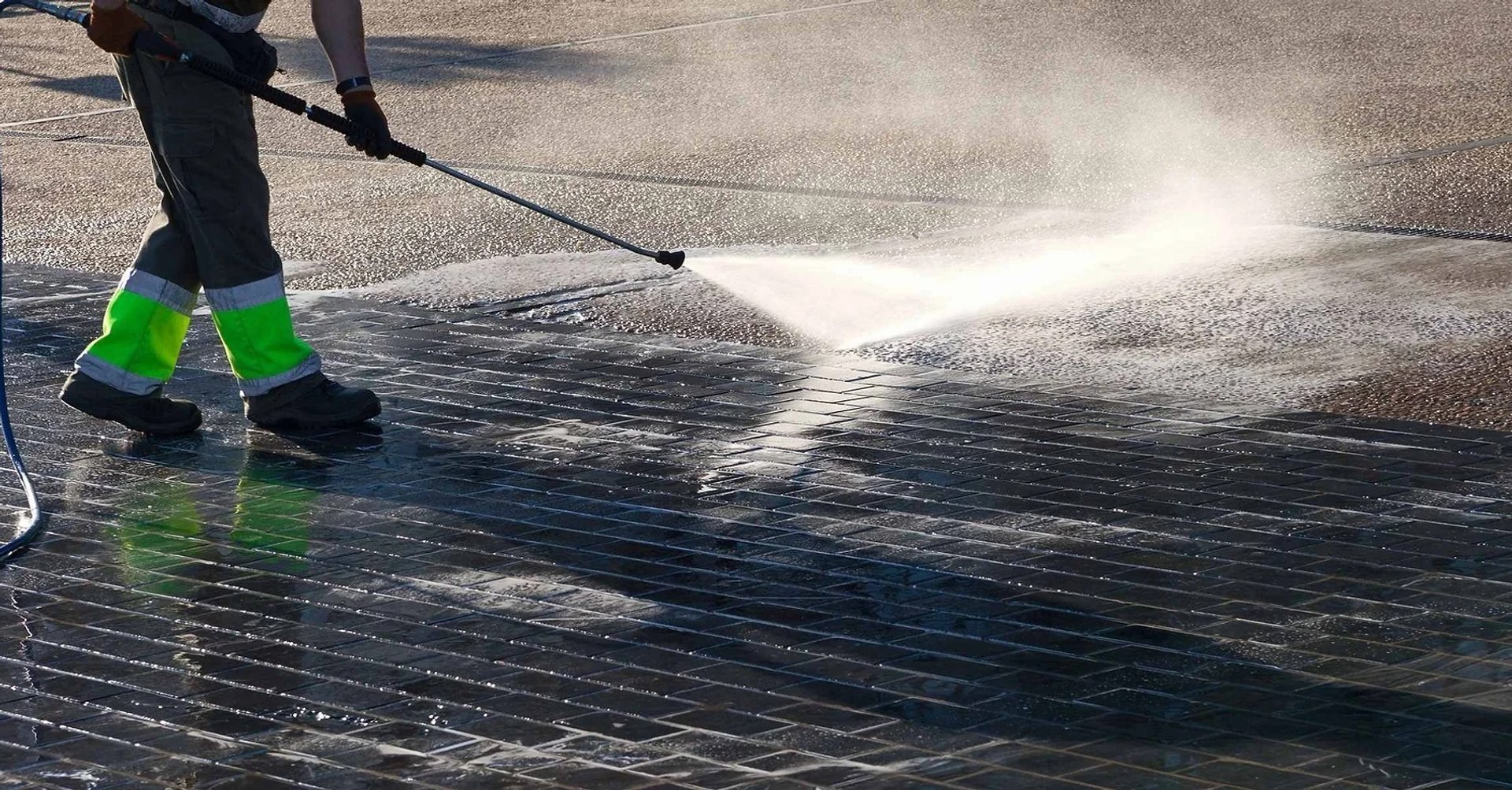 a man in a yellow vest is cleaning the street