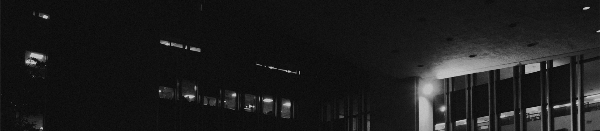 Fotografía conceptual en blanco y negro de un entorno urbano nocturno, con luces y sombras resaltando la arquitectura y la at