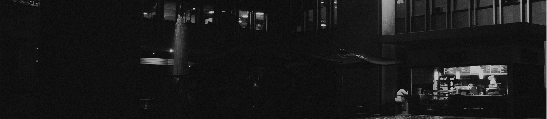 Fotografía conceptual en blanco y negro de un entorno urbano nocturno, con luces y sombras resaltando la arquitectura y la at