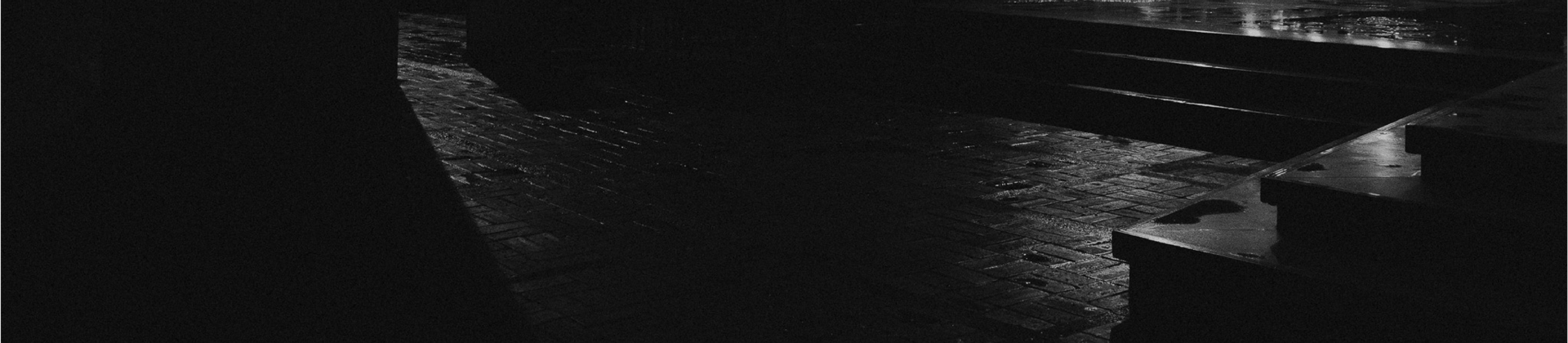 Fotografía conceptual en blanco y negro de un entorno urbano nocturno, con luces y sombras resaltando la arquitectura y la at