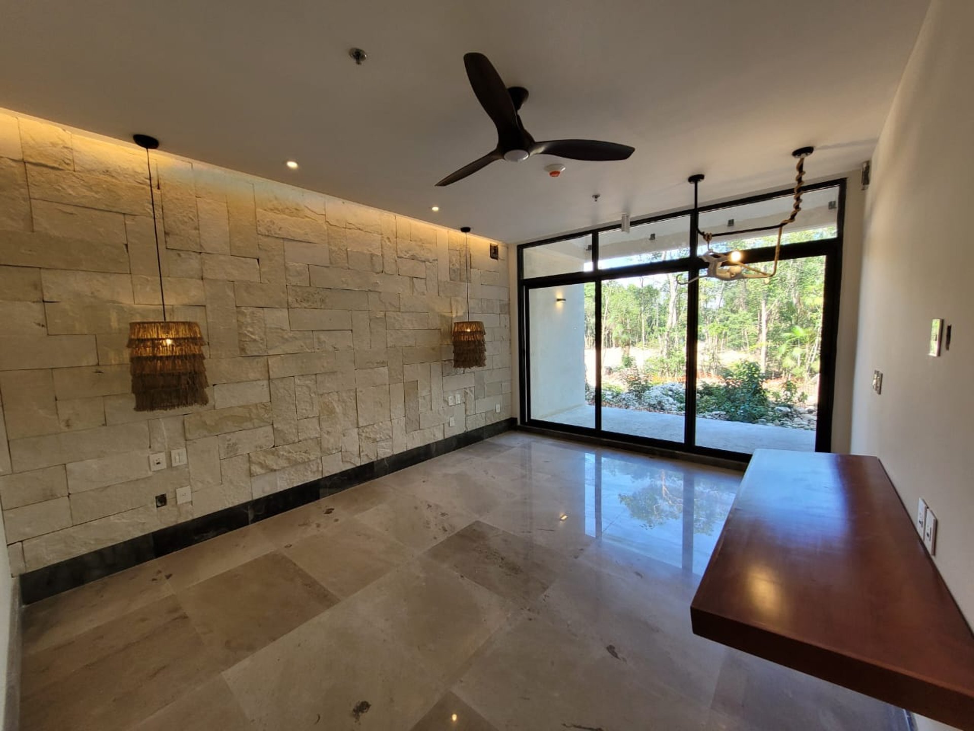 Imagen de espacio al interior de una casa remodelada con muros de piedra natural, pisos de mármol y ventanas de piso a techo