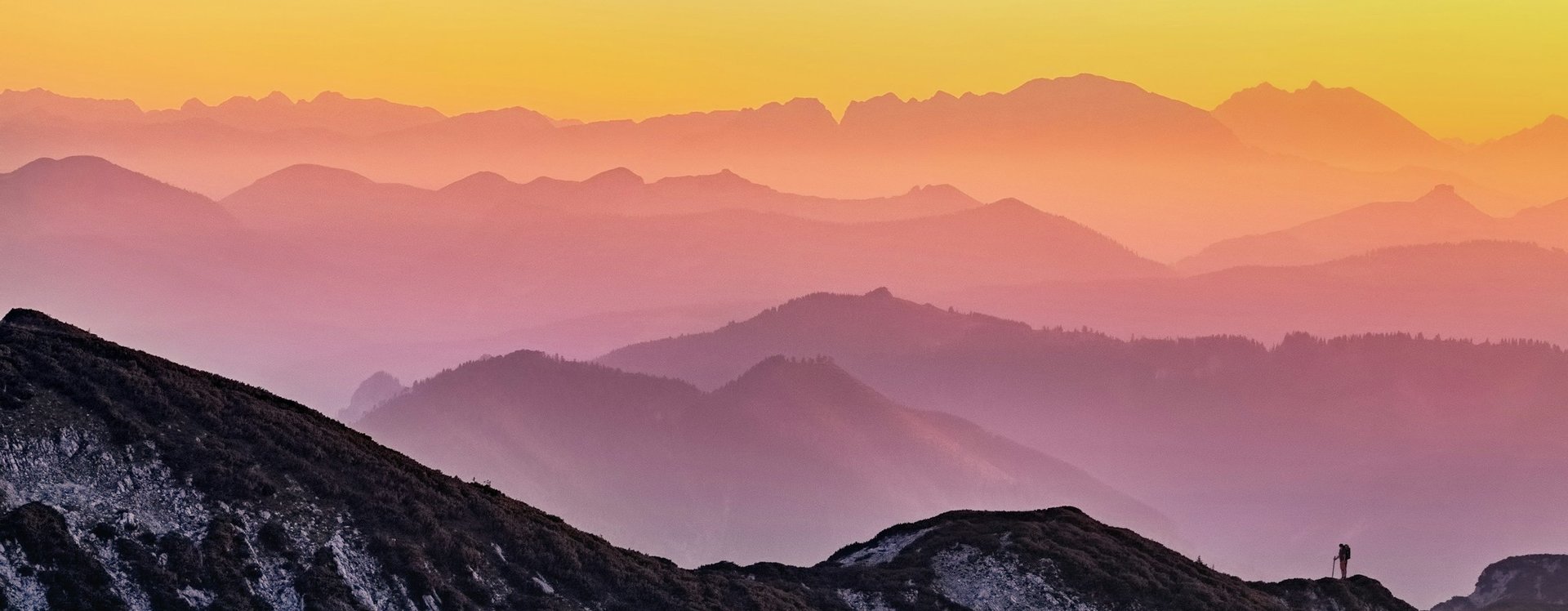 Multicoloured mountain range, with a hiker in the foreground