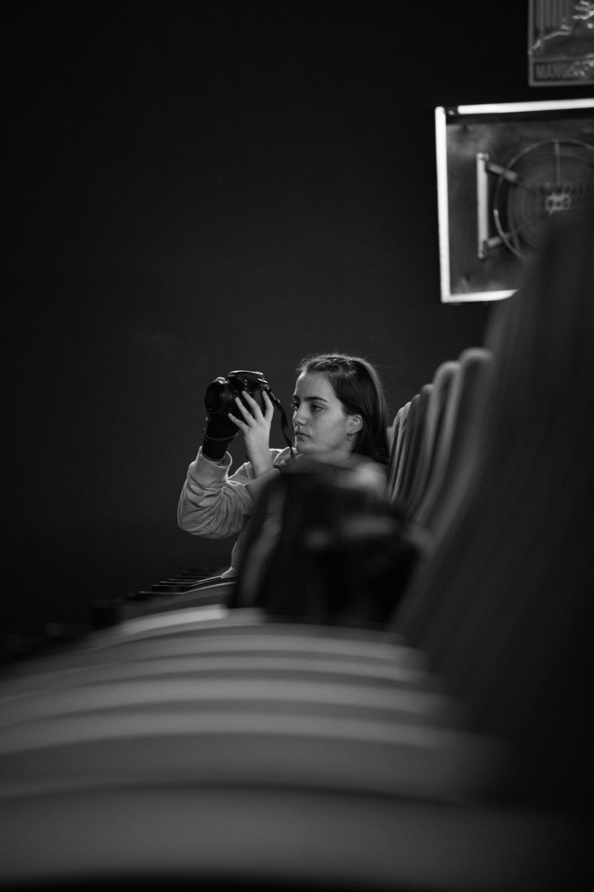 grayscale photo of man standing beside camera