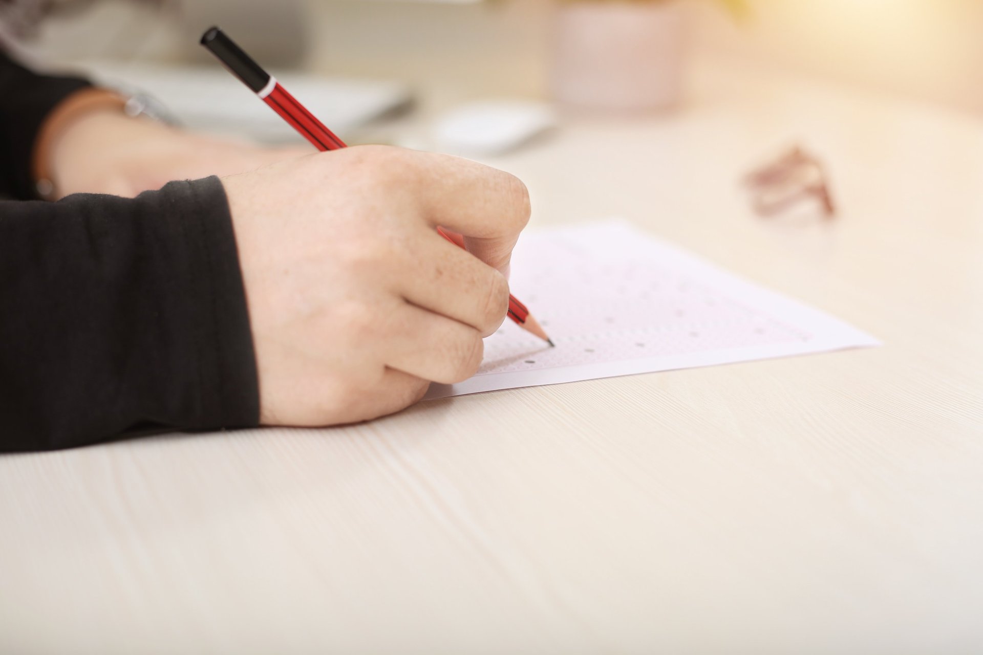 boy in green sweater writing on white paper