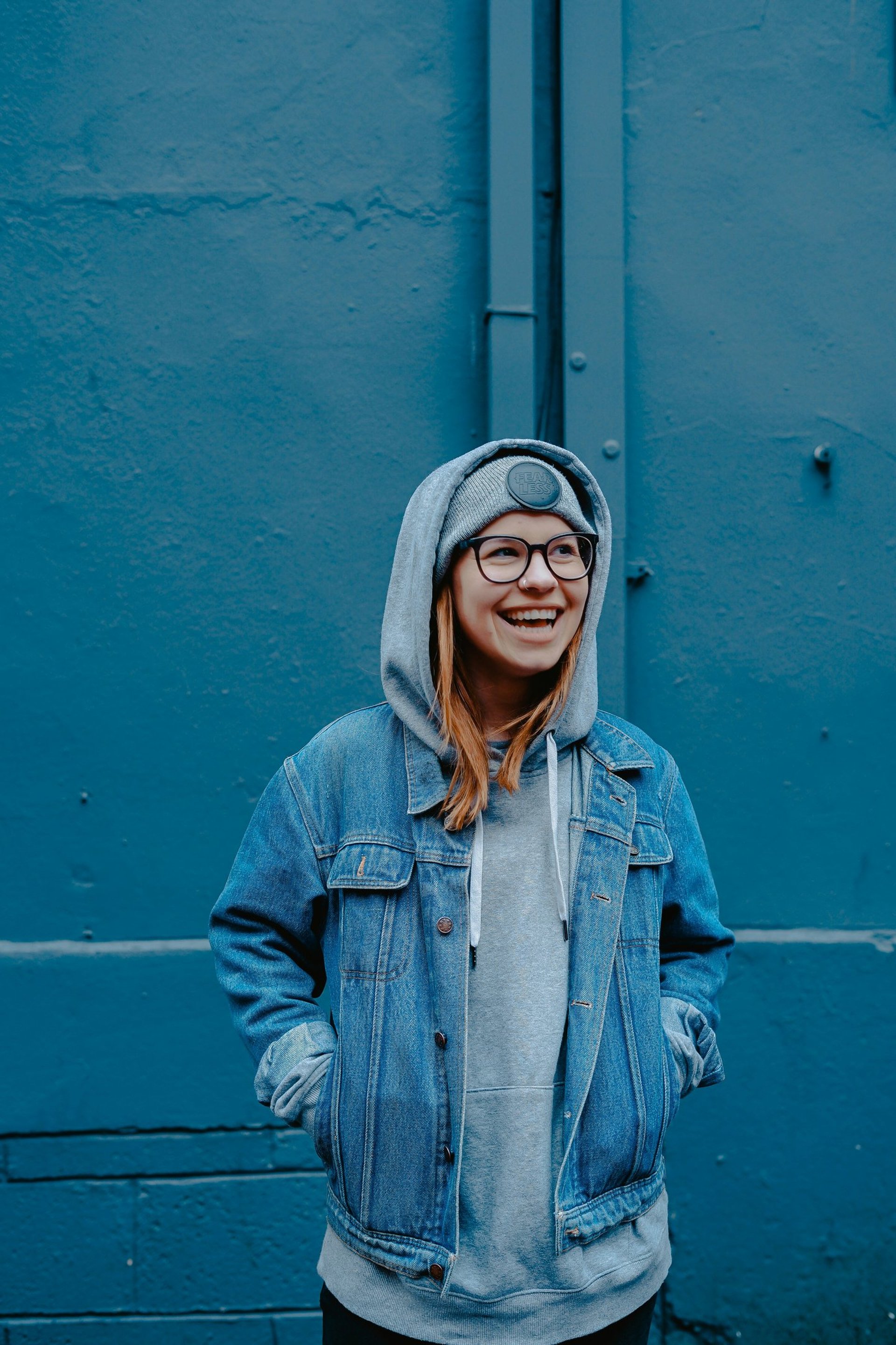 woman in blue jacket standing beside walls