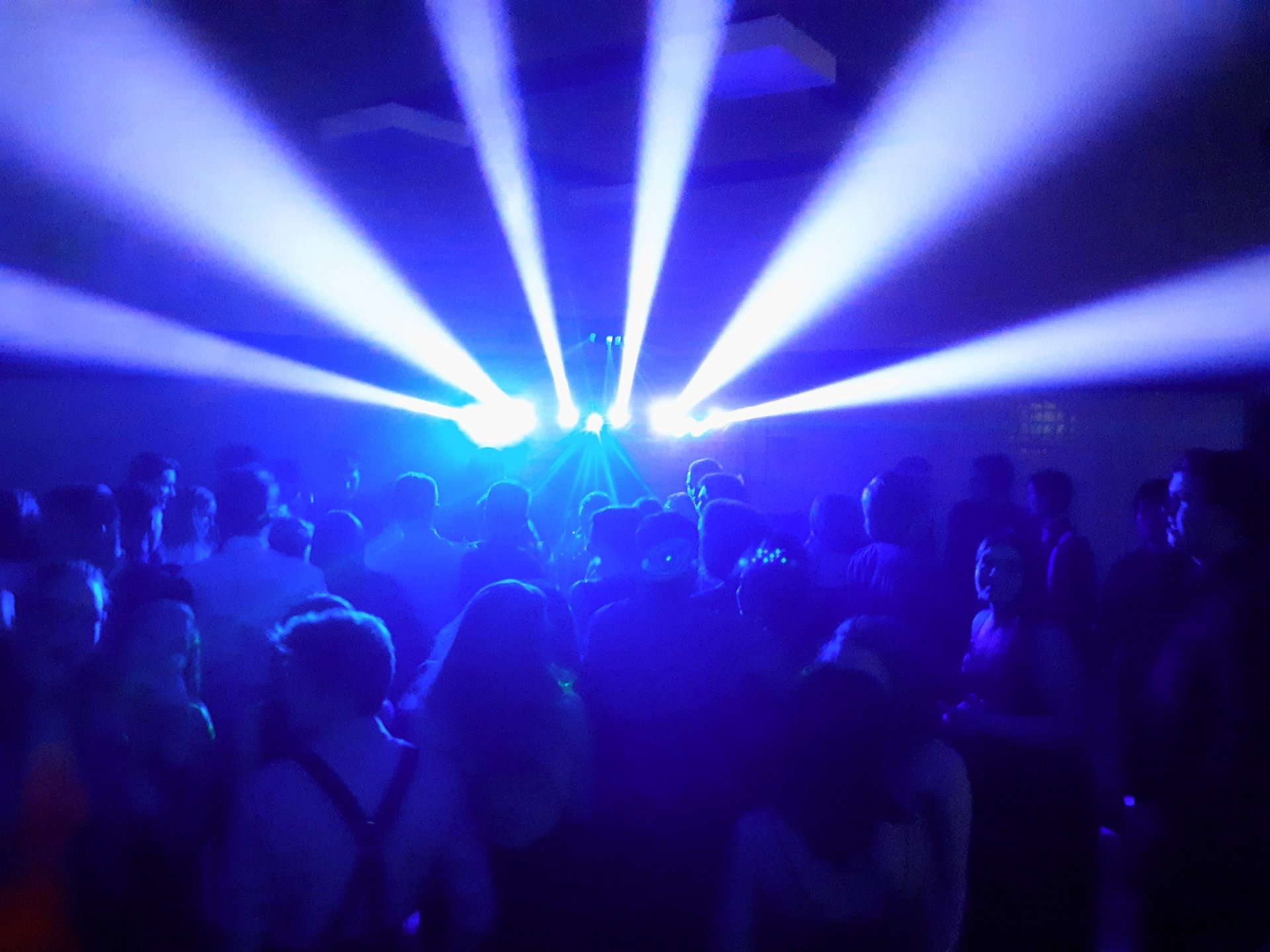 Sharp beams of light shoot over a full dancefloor of guests