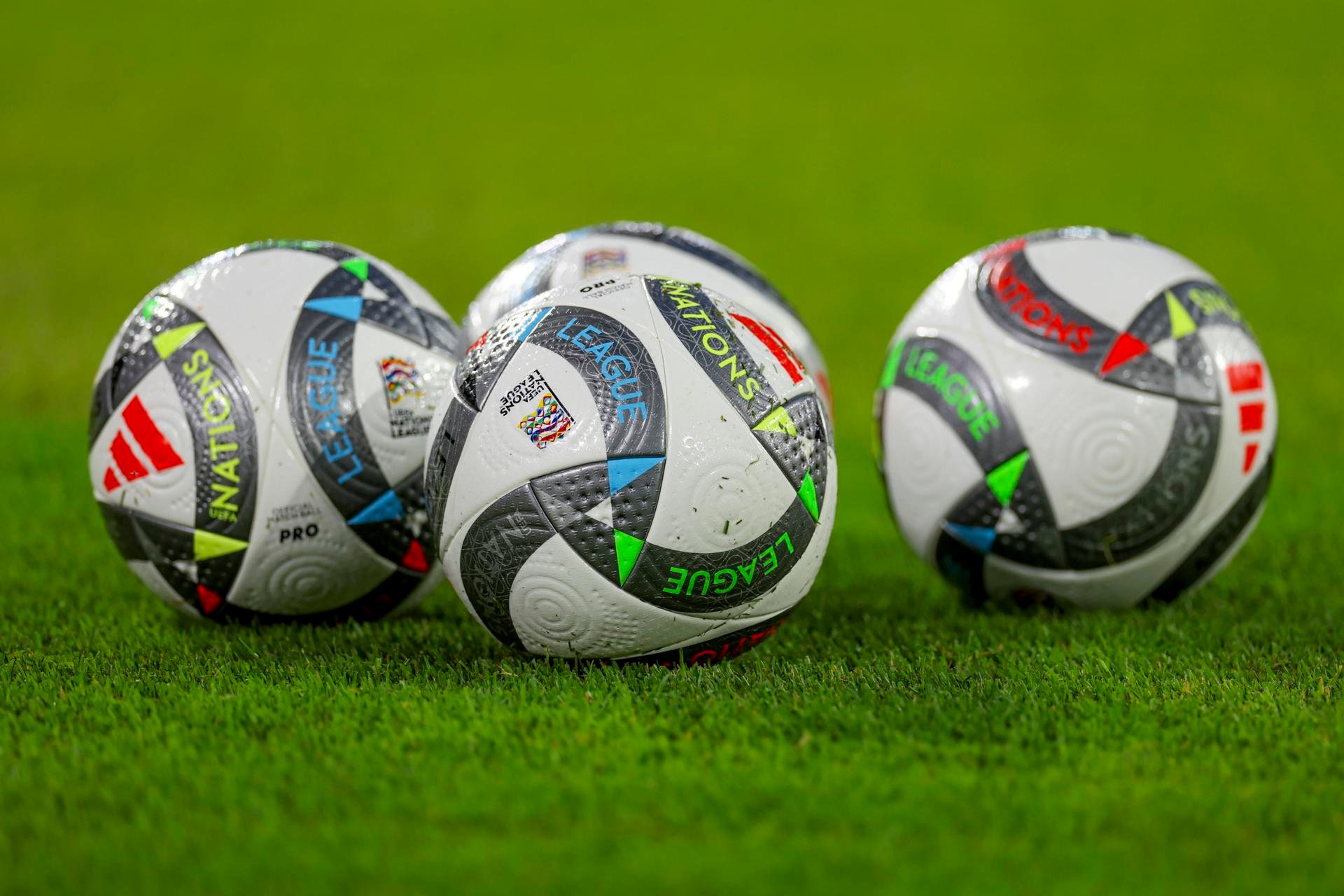 three white-and-black soccer balls on field