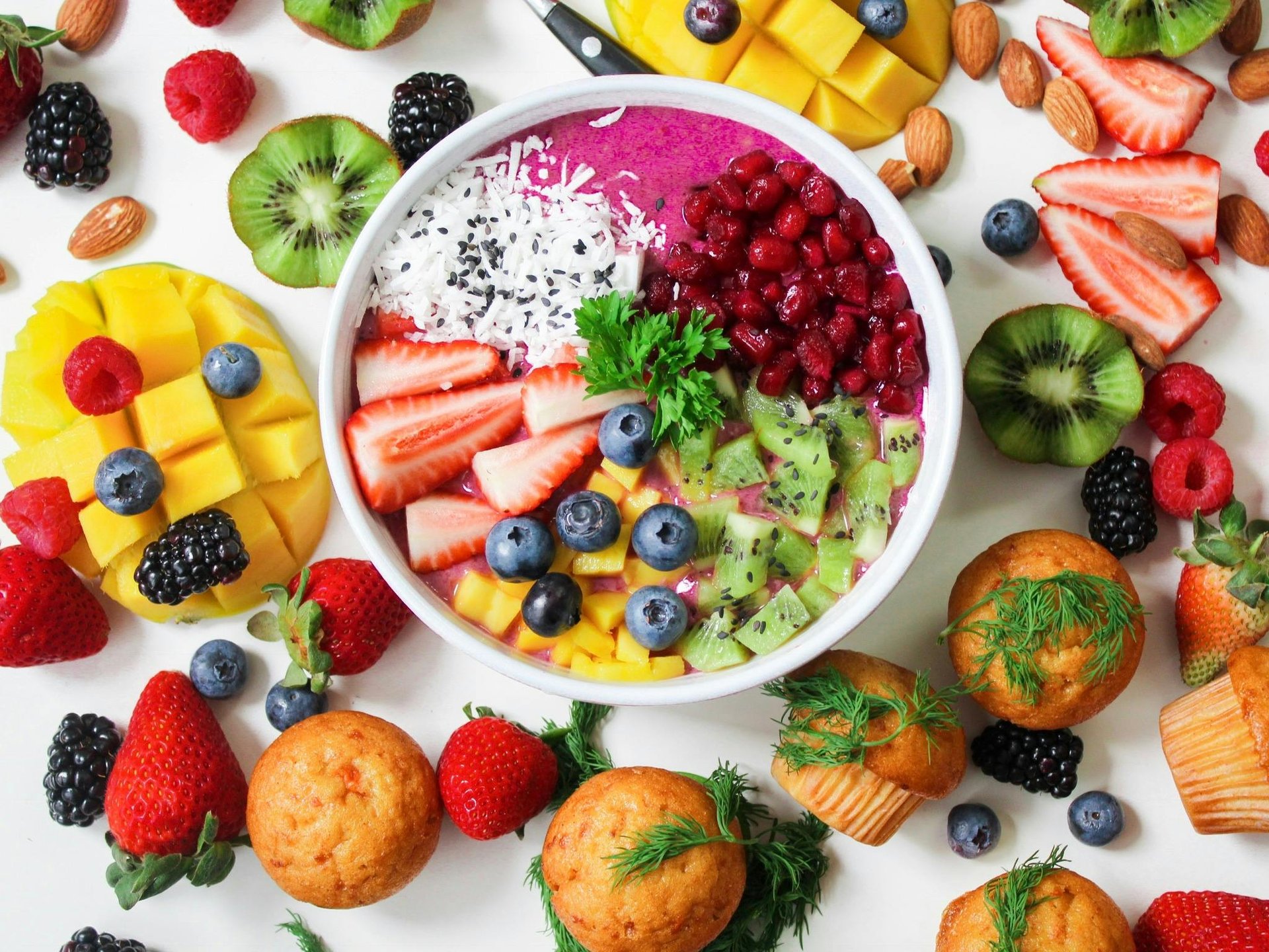 witte achtergrond met verschillende soorten fruit soorten met in het midden een schaal yoghurt met fruit erin