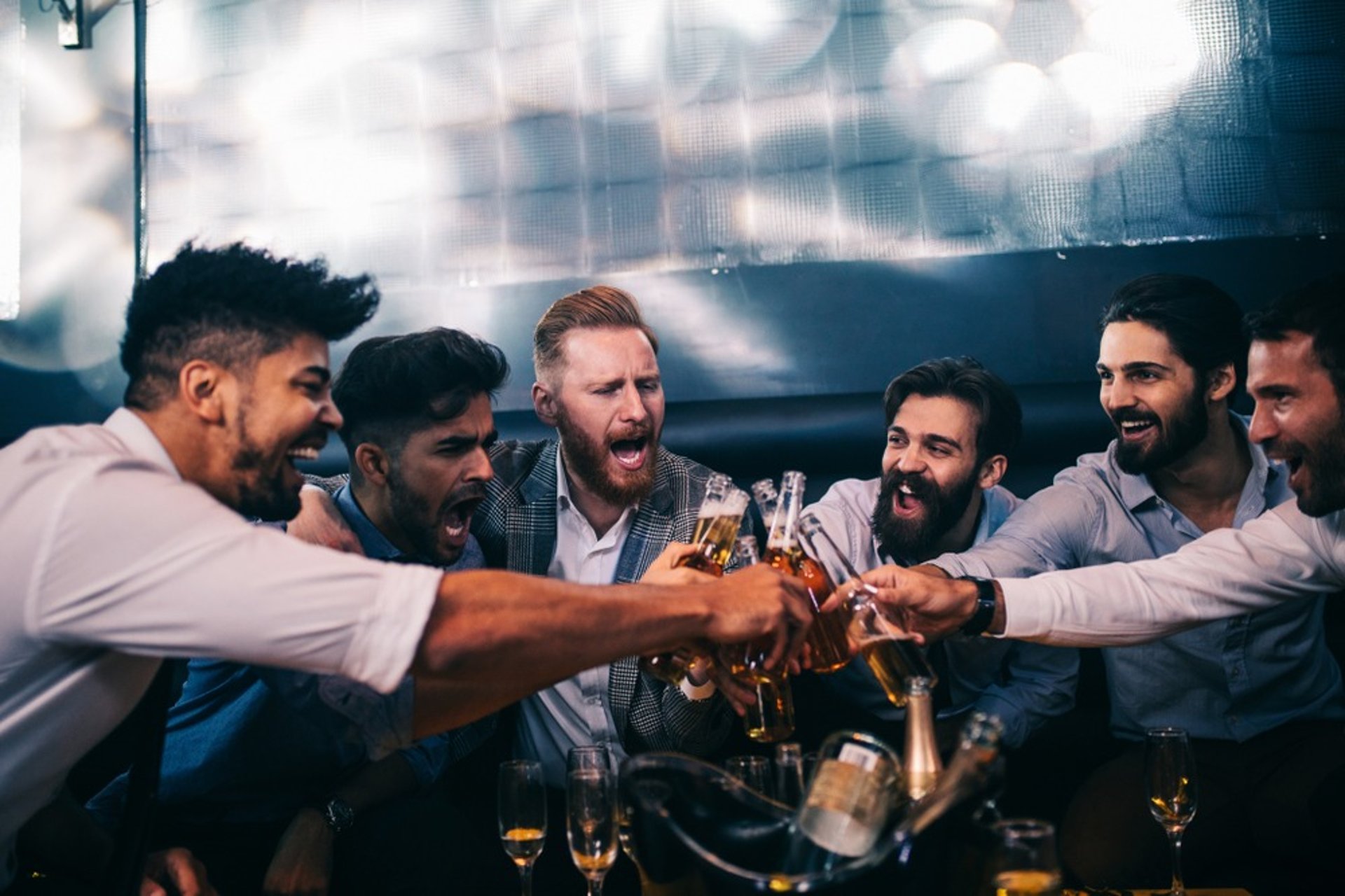 Group of men toasting with drinks on a Las Vegas bachelor party bus crawl, celebrating an epic night of fun and camaraderie.