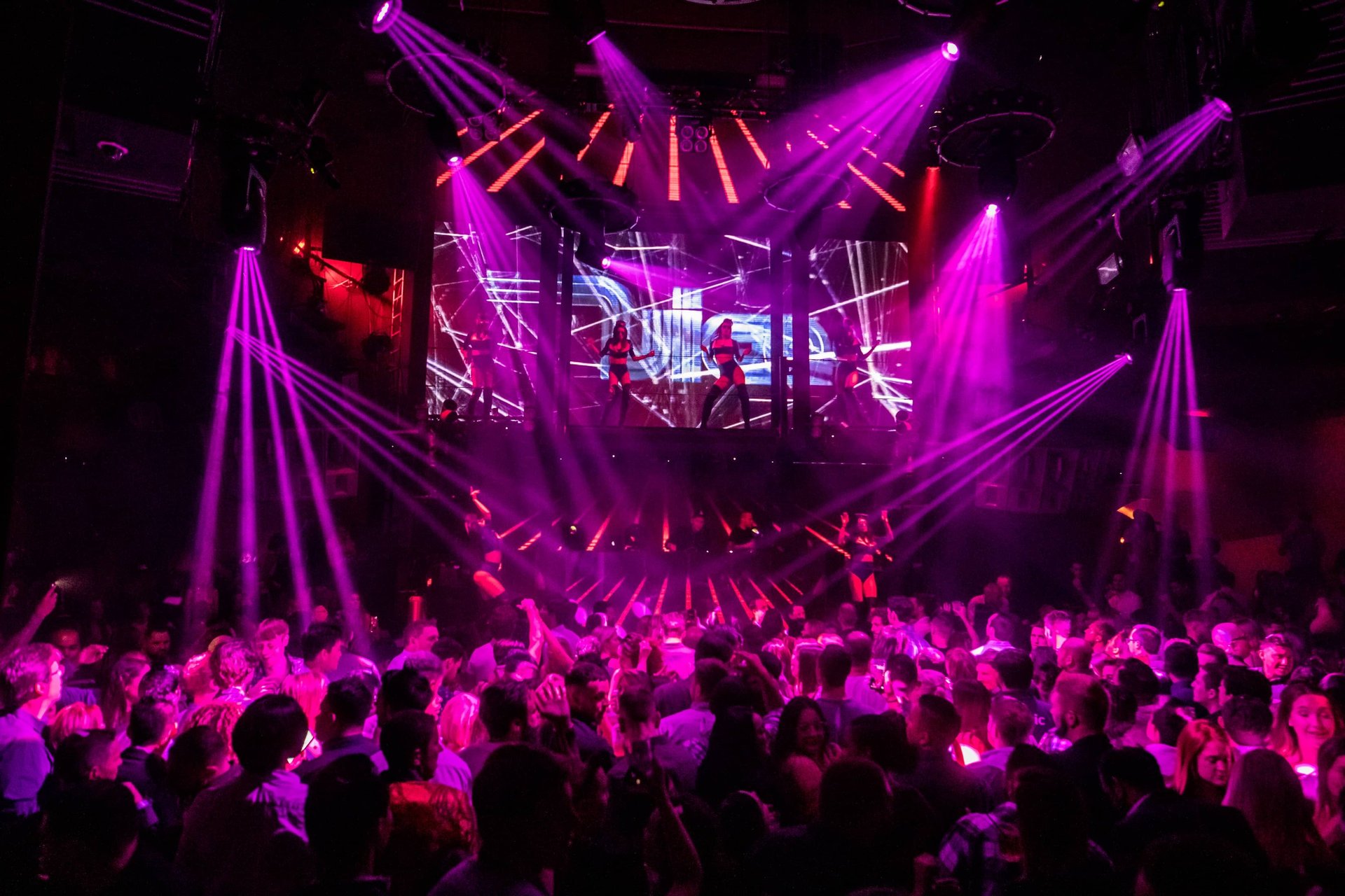 Las Vegas nightclub light show with DJ and partygoers on the dance floor