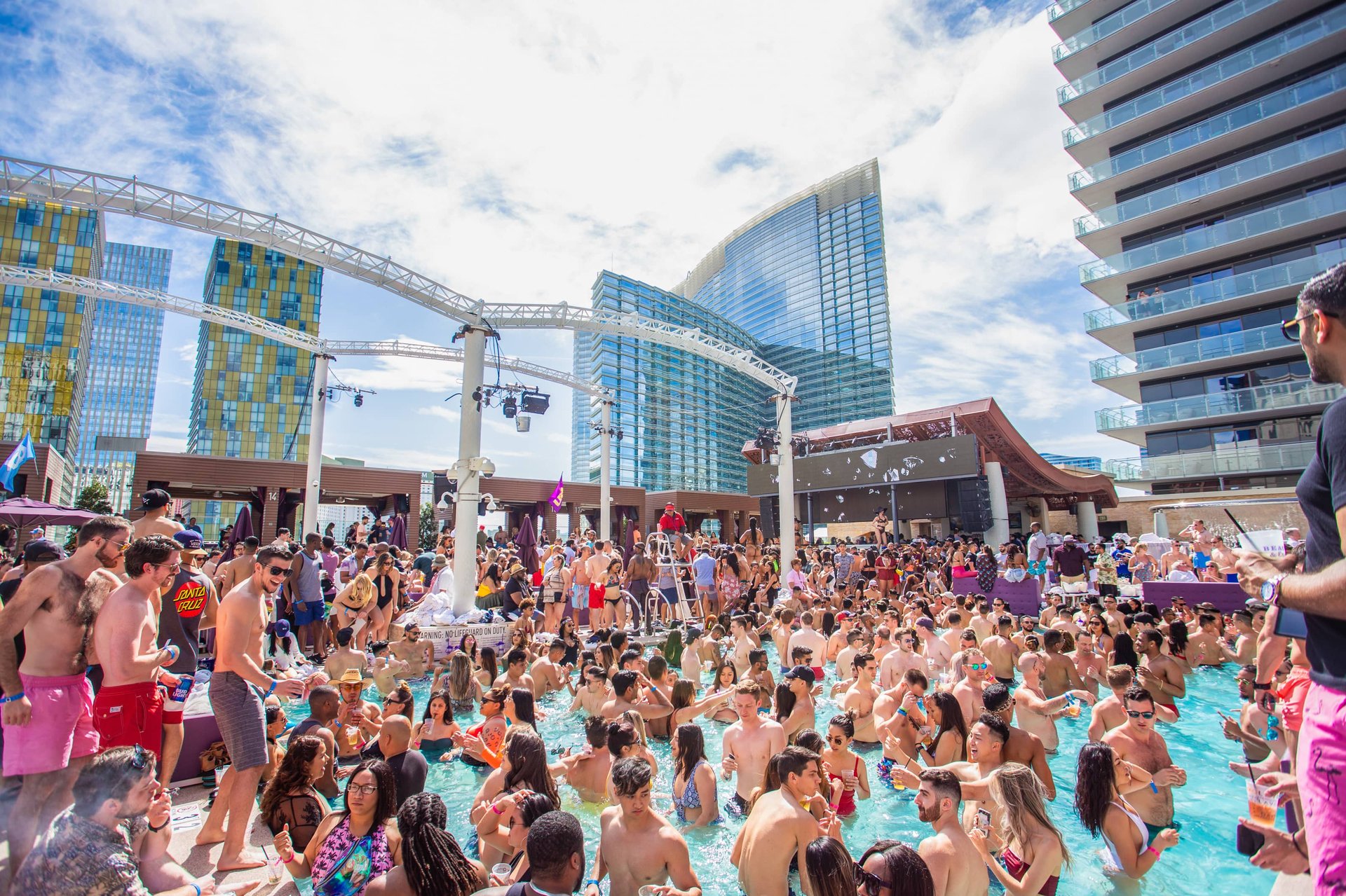 Crowd at a Las Vegas dayclub pool party during a VIP party bus tour with music and drinks.