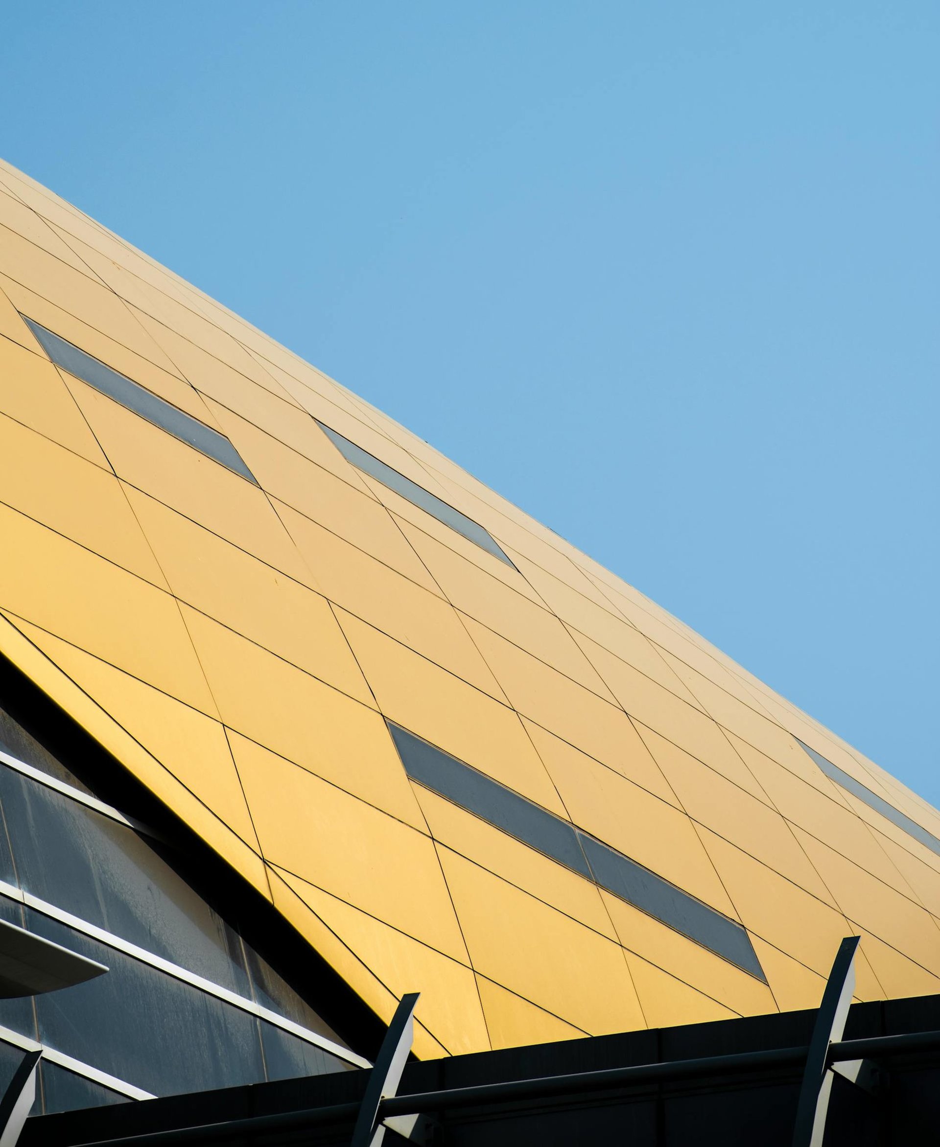 an abstract photo of a curved building with a blue sky in the background