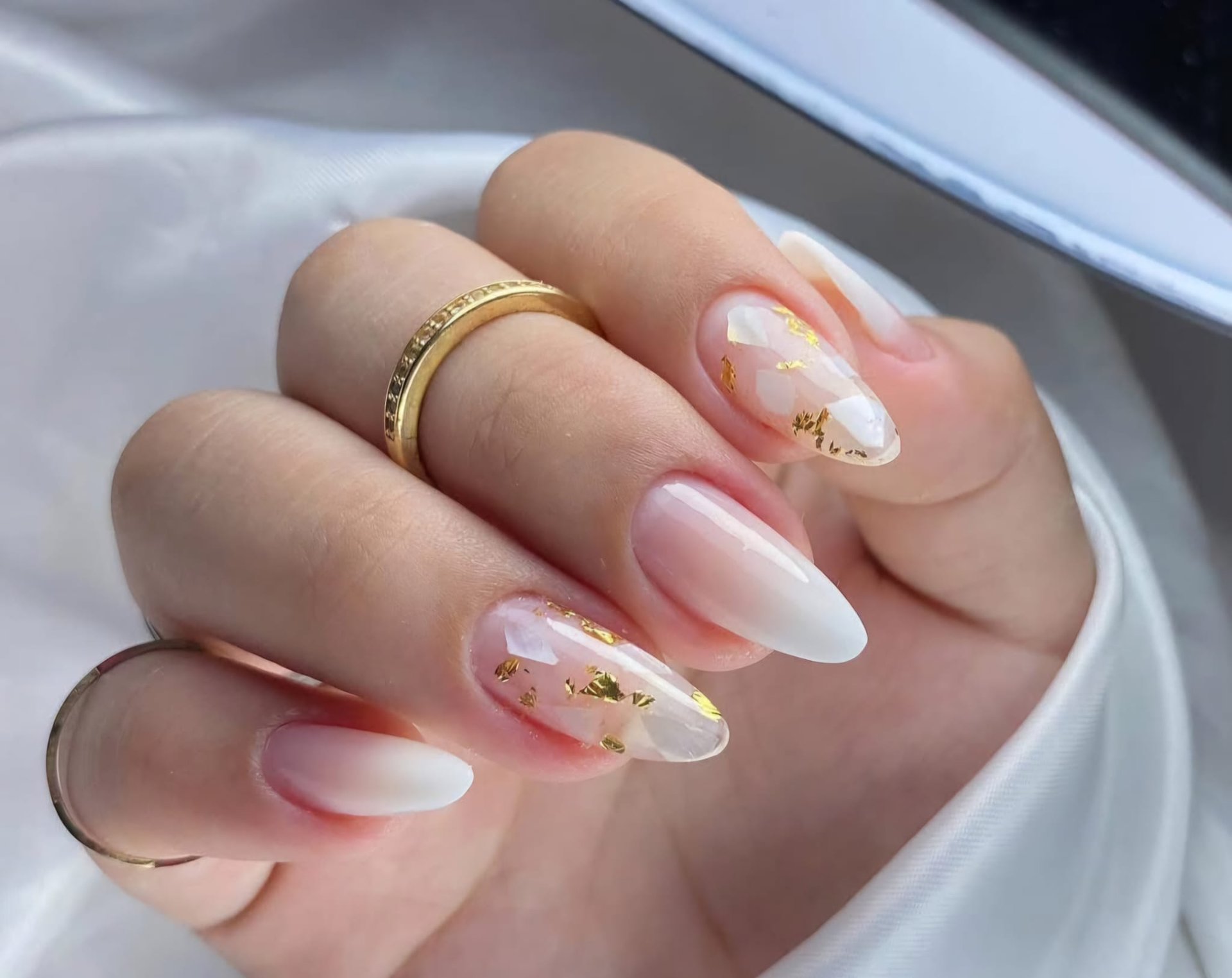 person with pink manicure on white textile