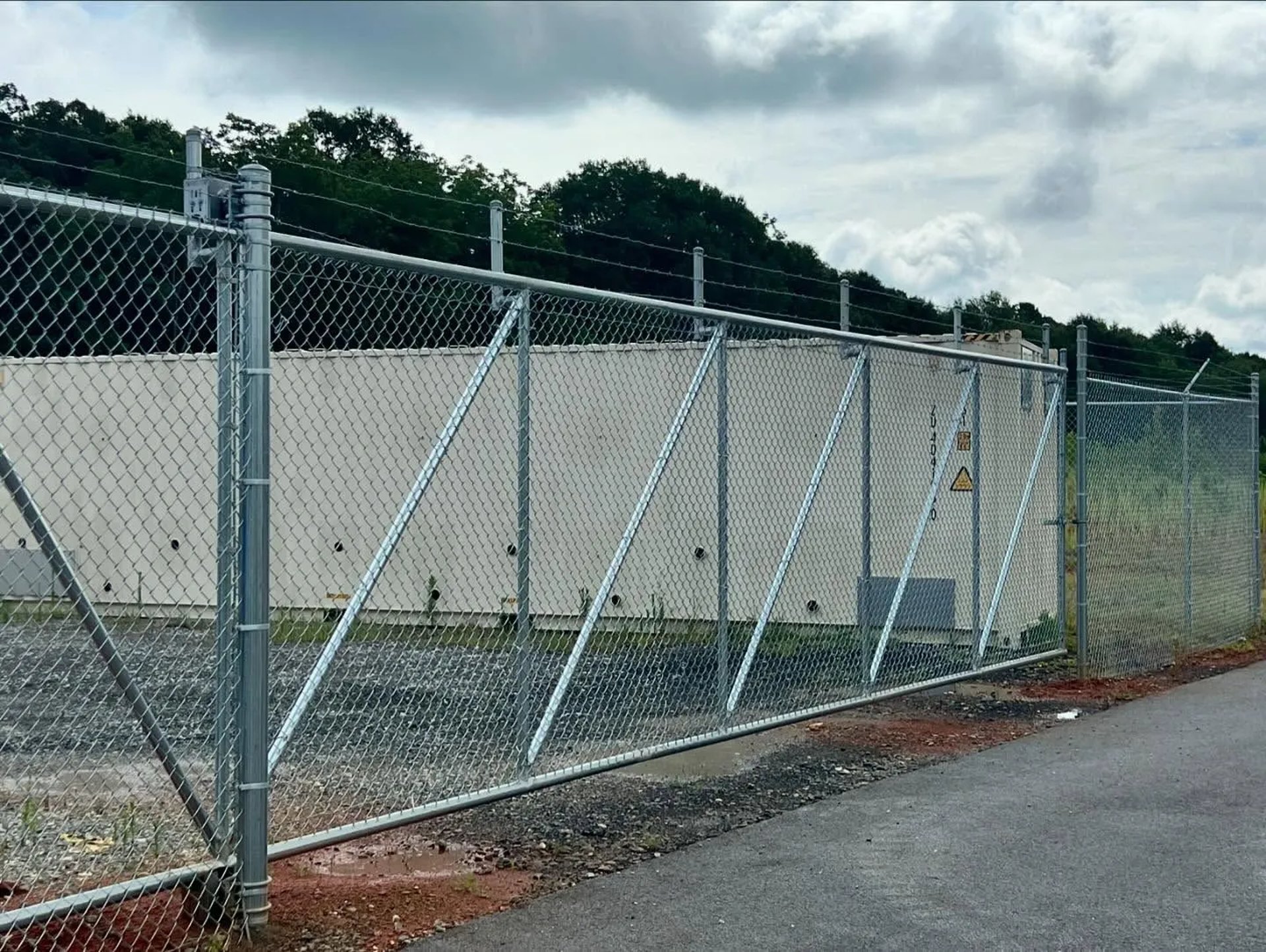 black metal gate near green grass and trees during daytime