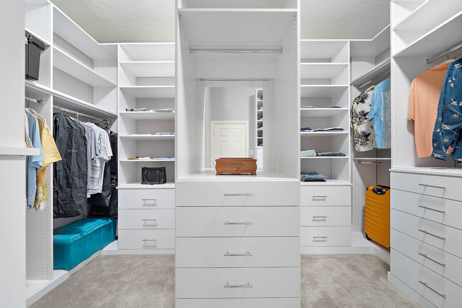 A walk in closet with clothes and a handbag