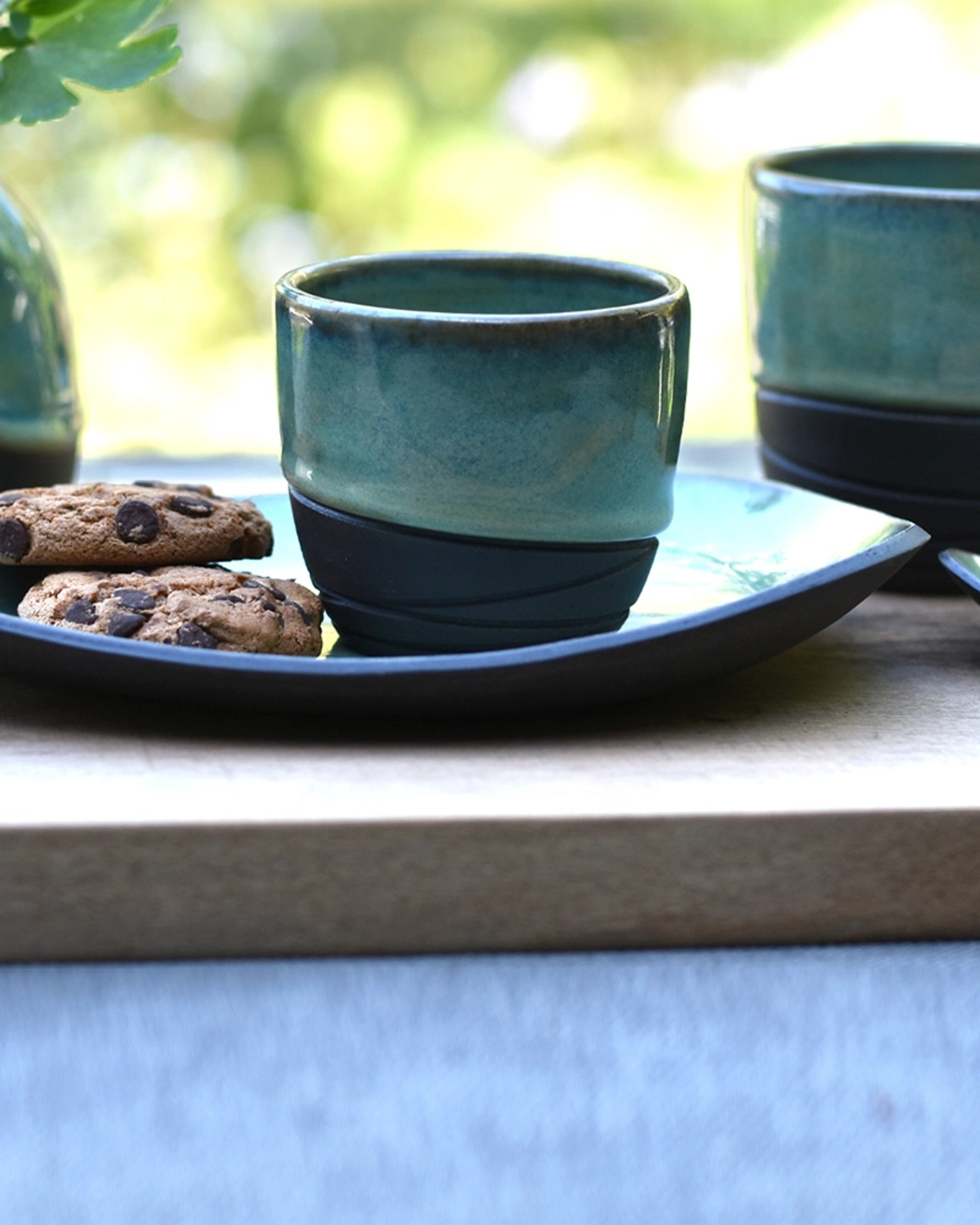 Handgemaakte keramieken koffiekopjes met schoteltje zwarte steengoed klei met sage groene glazuur