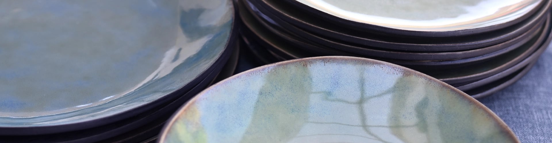 Detail handgemaakte borden zwart met blauw groene glazuur