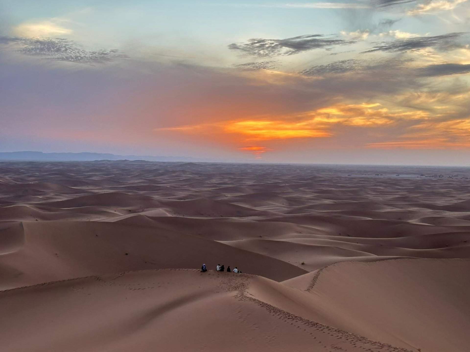 two men sitting on sand dunes
