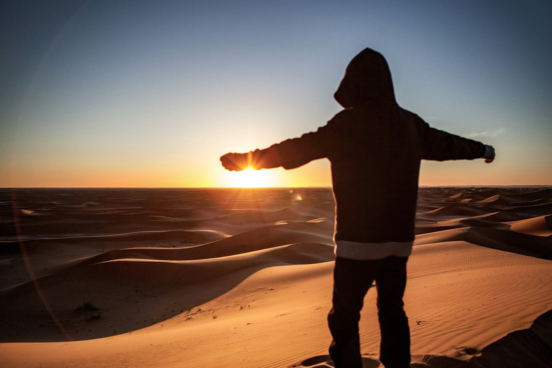 two men sitting on sand dunes