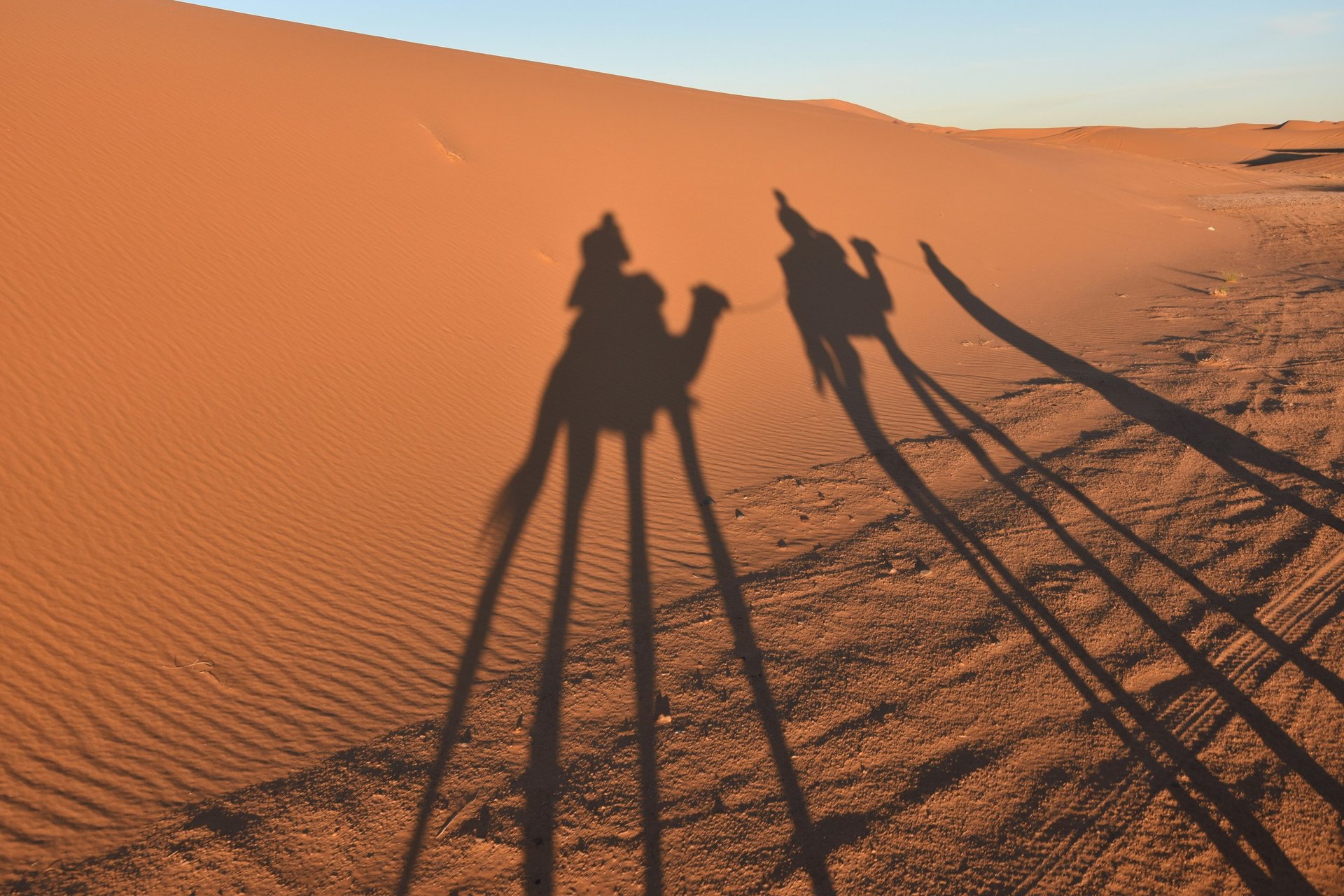 two men sitting on sand dunes