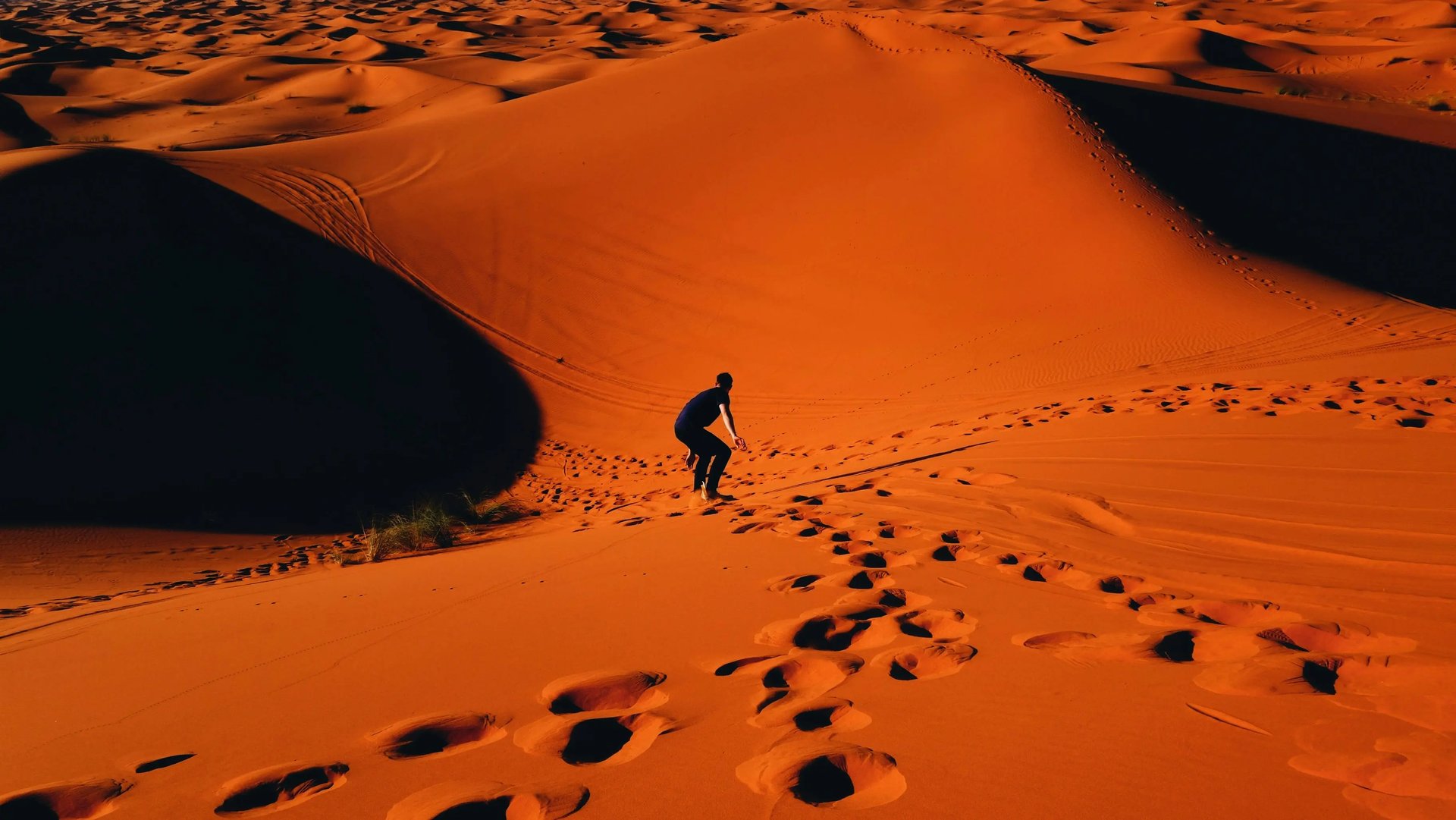 two men sitting on sand dunes