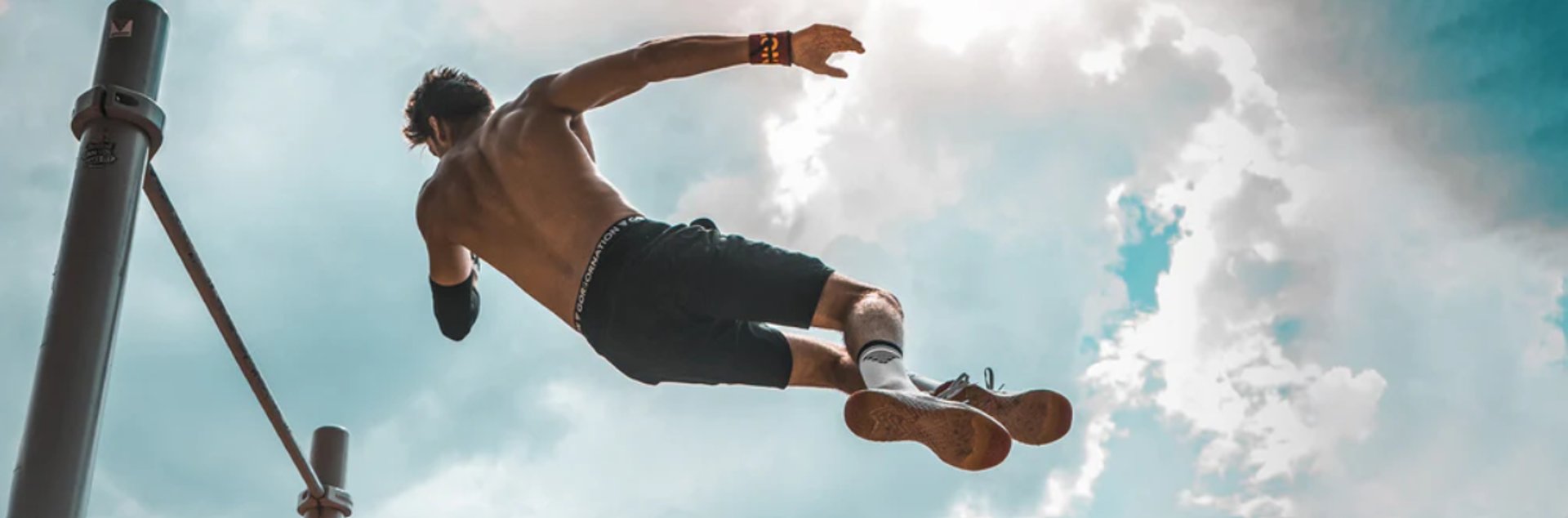 topless man in black shorts holding orange bar