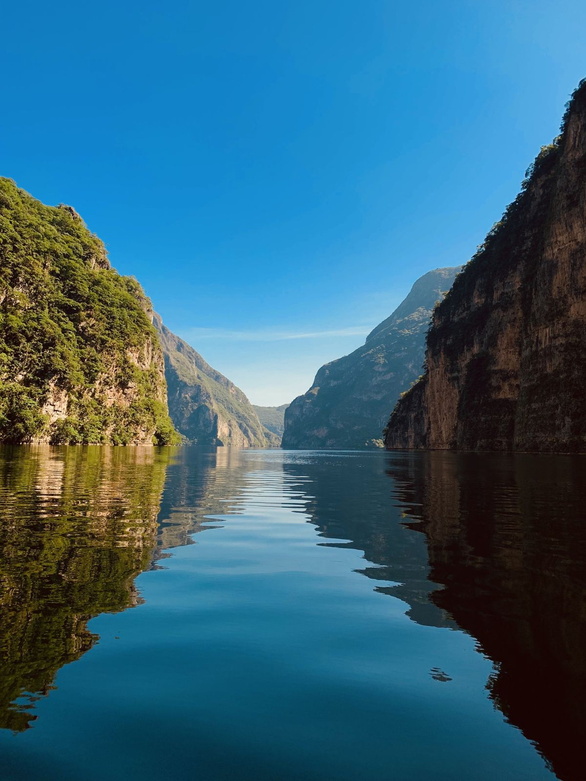 blue sea beside brown rocky mountain under blue sky during daytime