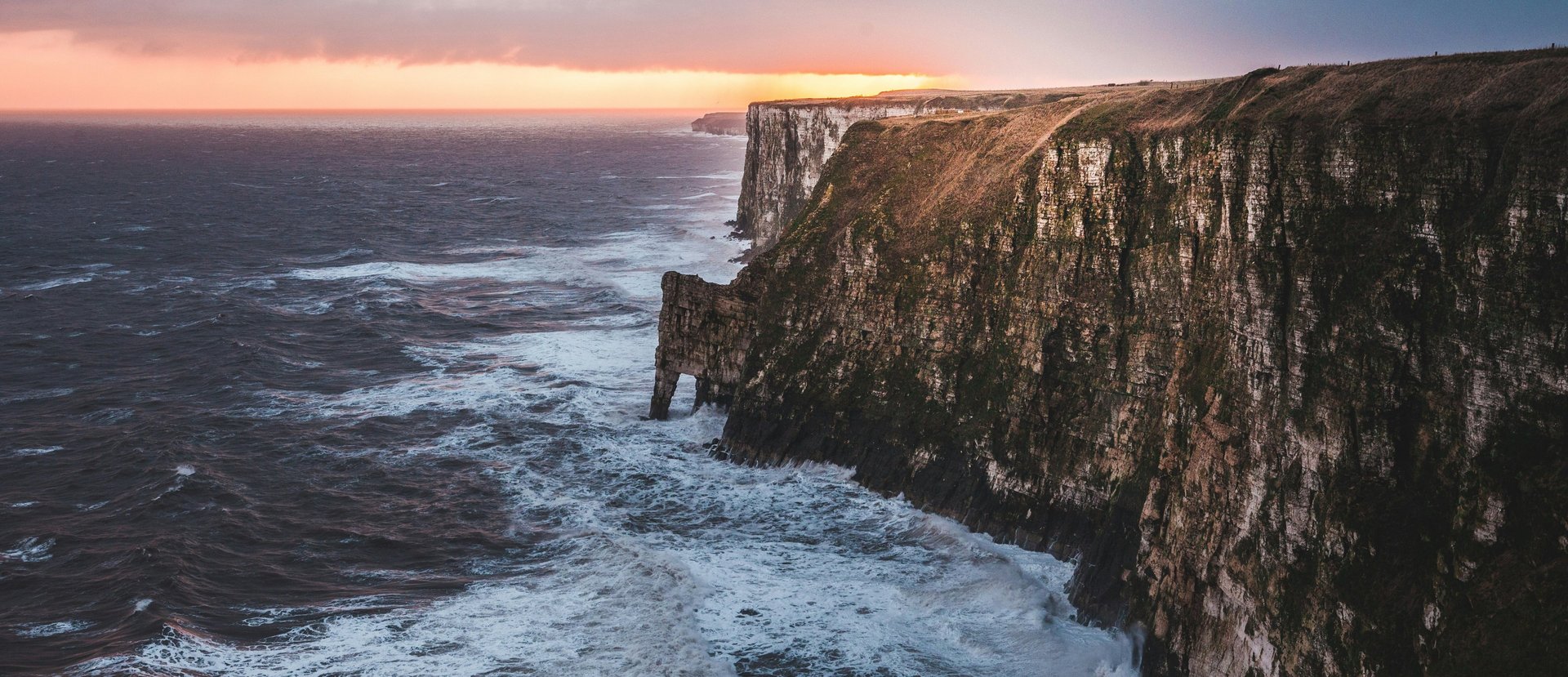 A cliff overlooking a body of water on a sunny day