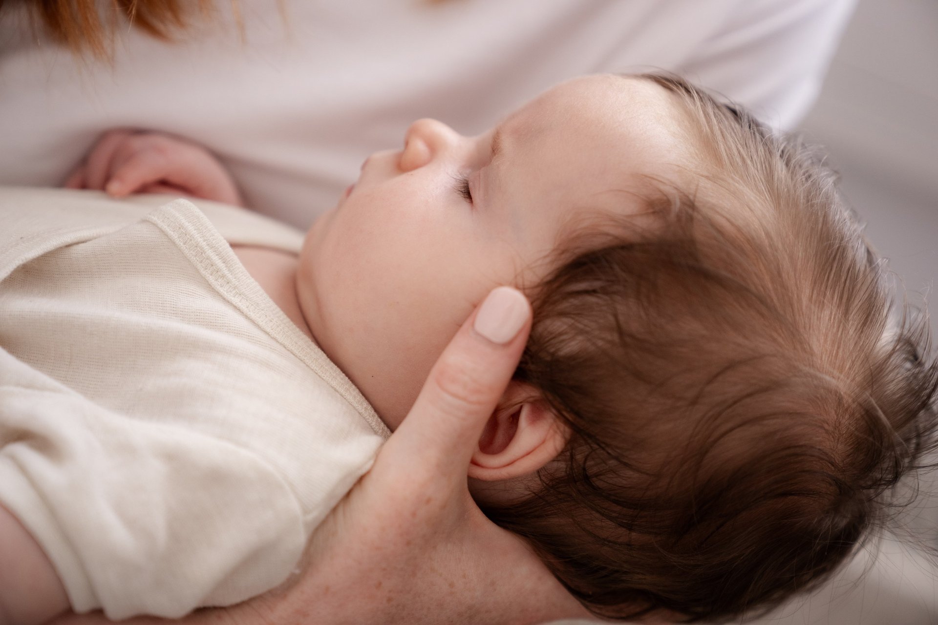 a woman holding a baby on top of a bed