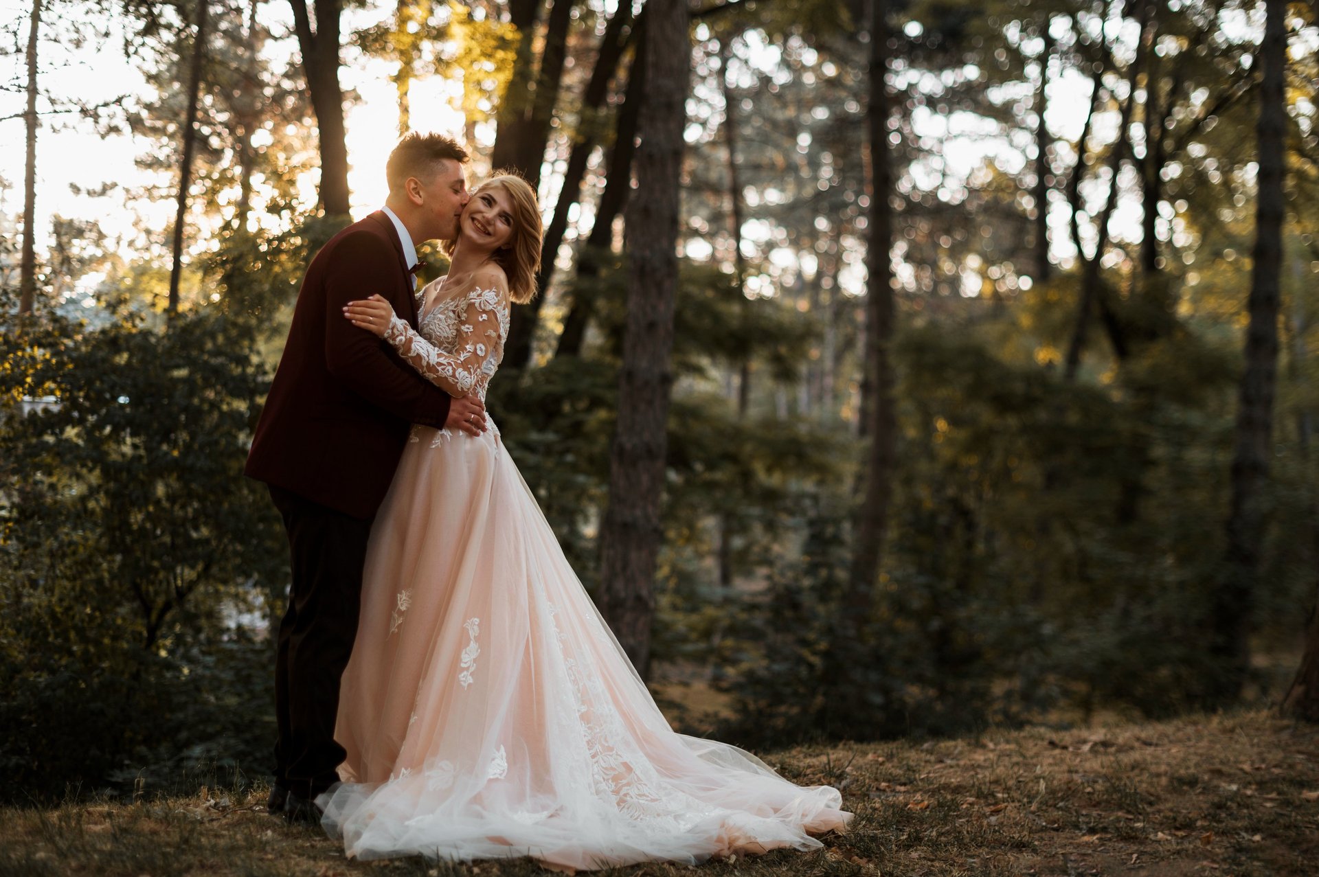man in blue suit kissing woman in white sleeveless dress
