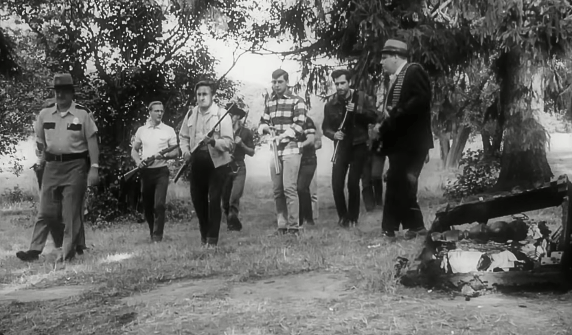 Screen shot from the 1968 film Night of the Living Dead showing a group of white men holding guns.
